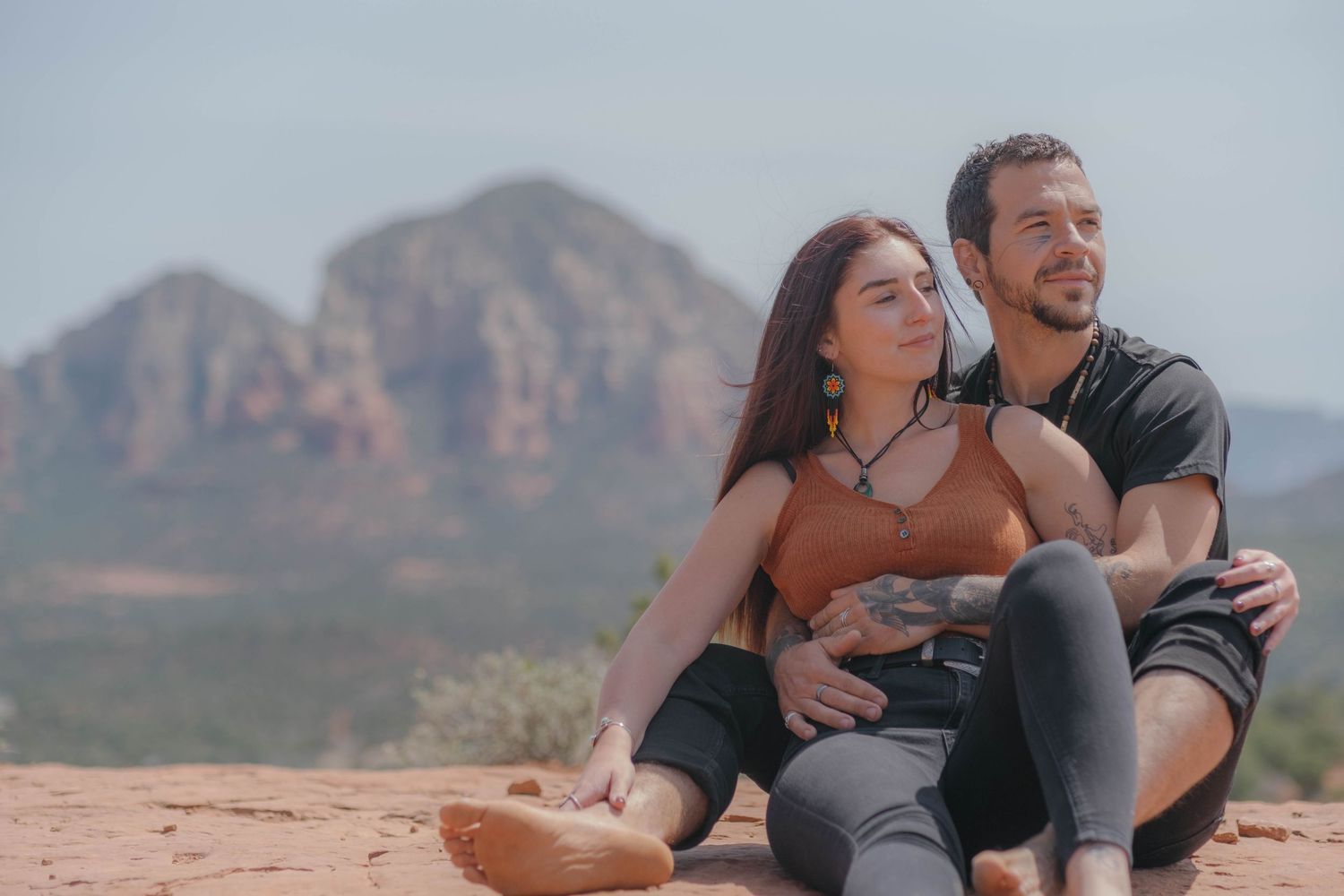 Couple sitting on a rock ledge, looking out over canyon vistas.