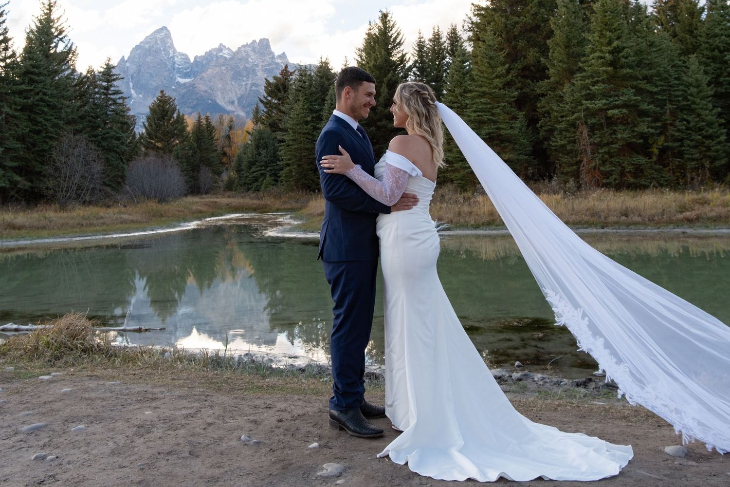 A romantic wedding photo session in front of majestic mountain peaks and evergreen forest at sunset.