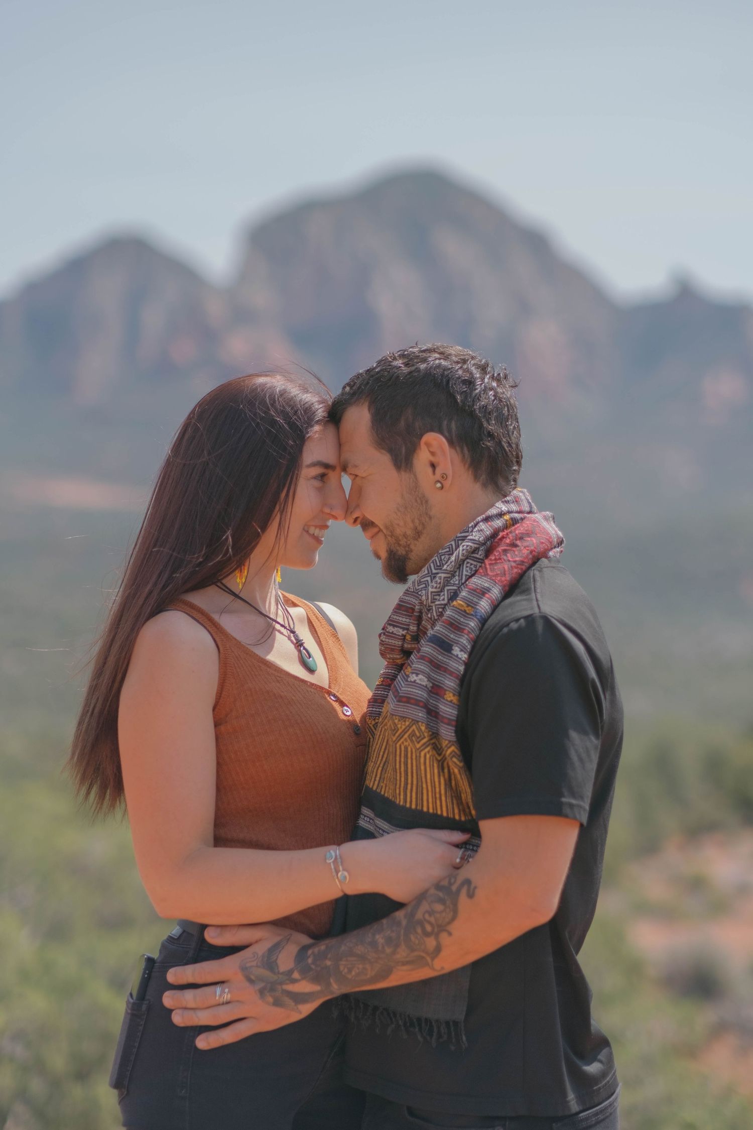 Close-up of couple touching foreheads during a high noon shoot in the red rocks of Sedona, Arizona.