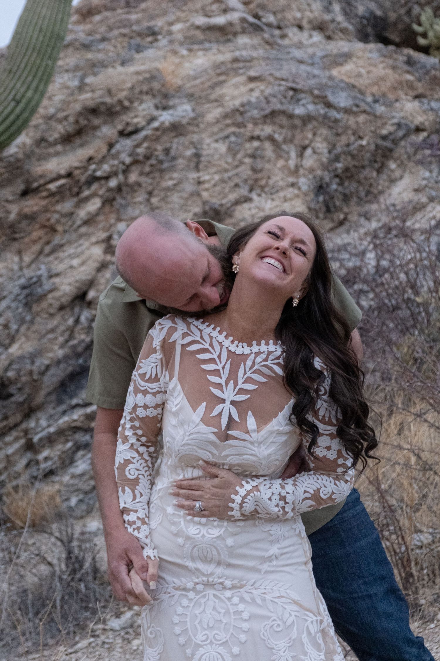 A couple shares a joyful moment together against a rocky desert backdrop during their elopement.