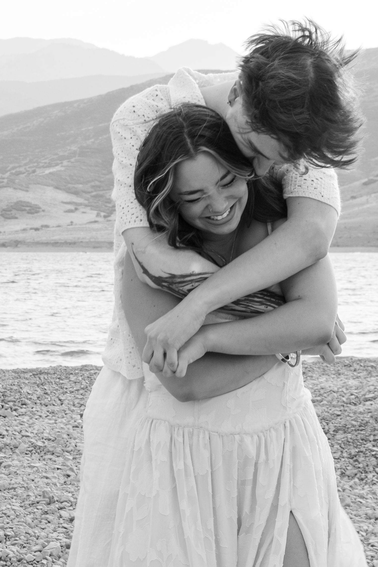A series of black and white photographs showing a person in a flowing white dress on a beach with mountains in the background.