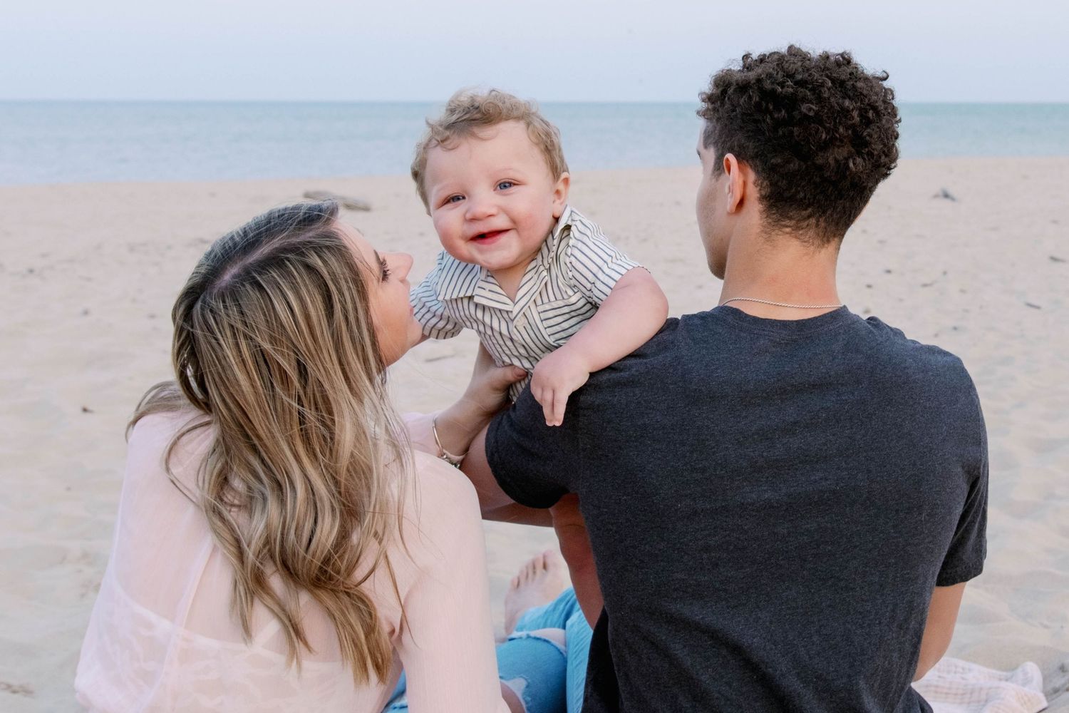 A family enjoys a tender moment together while sitting on a peaceful beach.