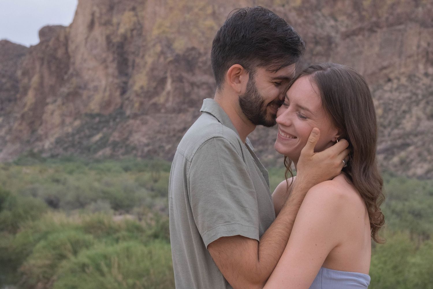 A romantic moment shared between a couple with red rock formations in the background.