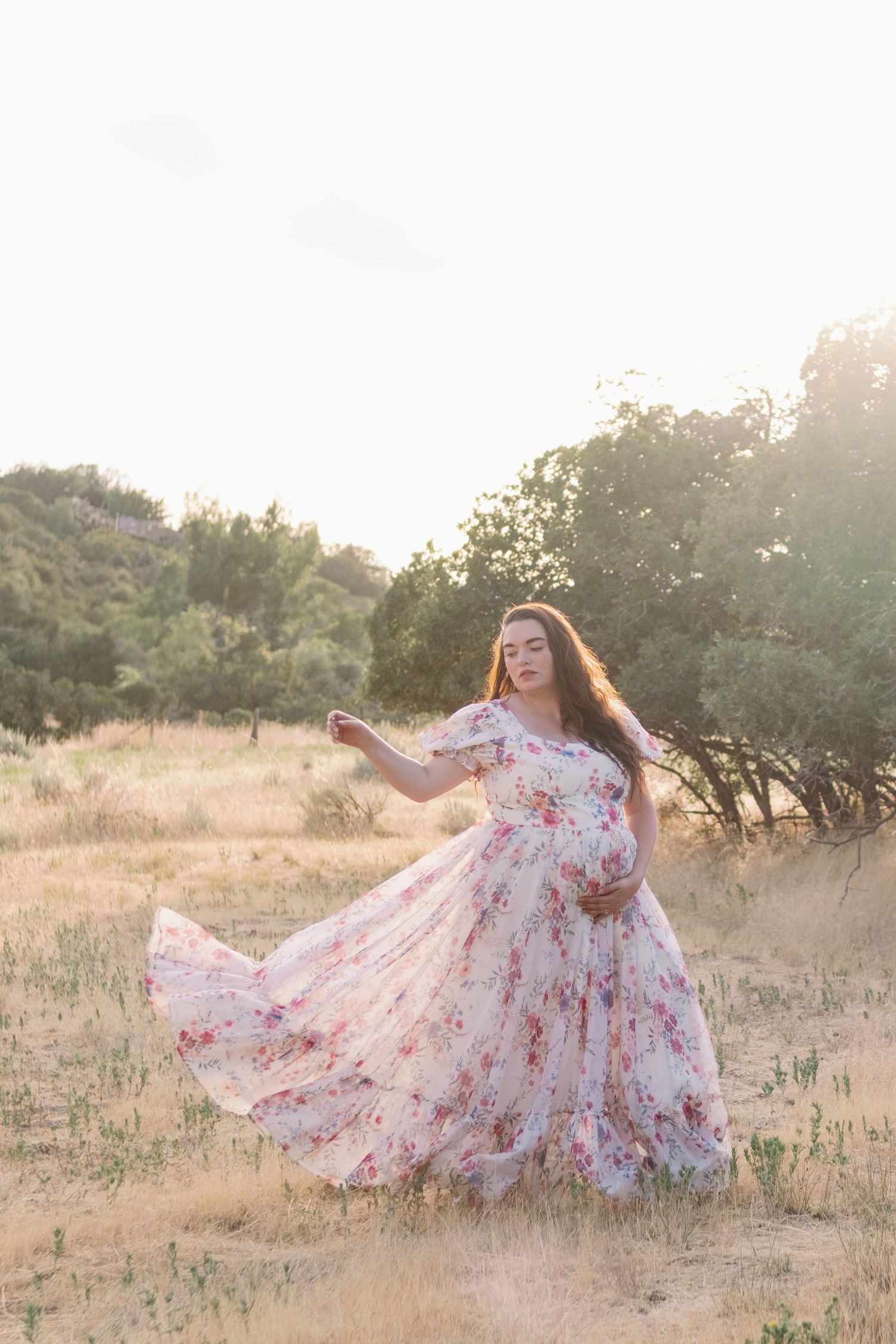 A flowy floral dress twirls gracefully in a sunlit field during golden hour, creating a dreamy summer scene.