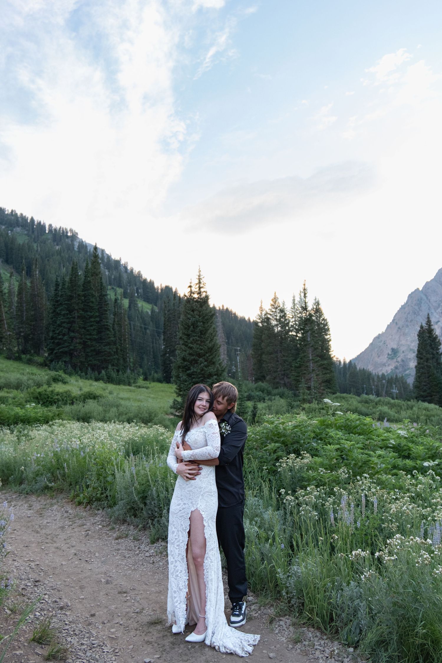Romantic mountain wedding photoshoot set against dramatic peaks and wildflowers in an alpine meadow.