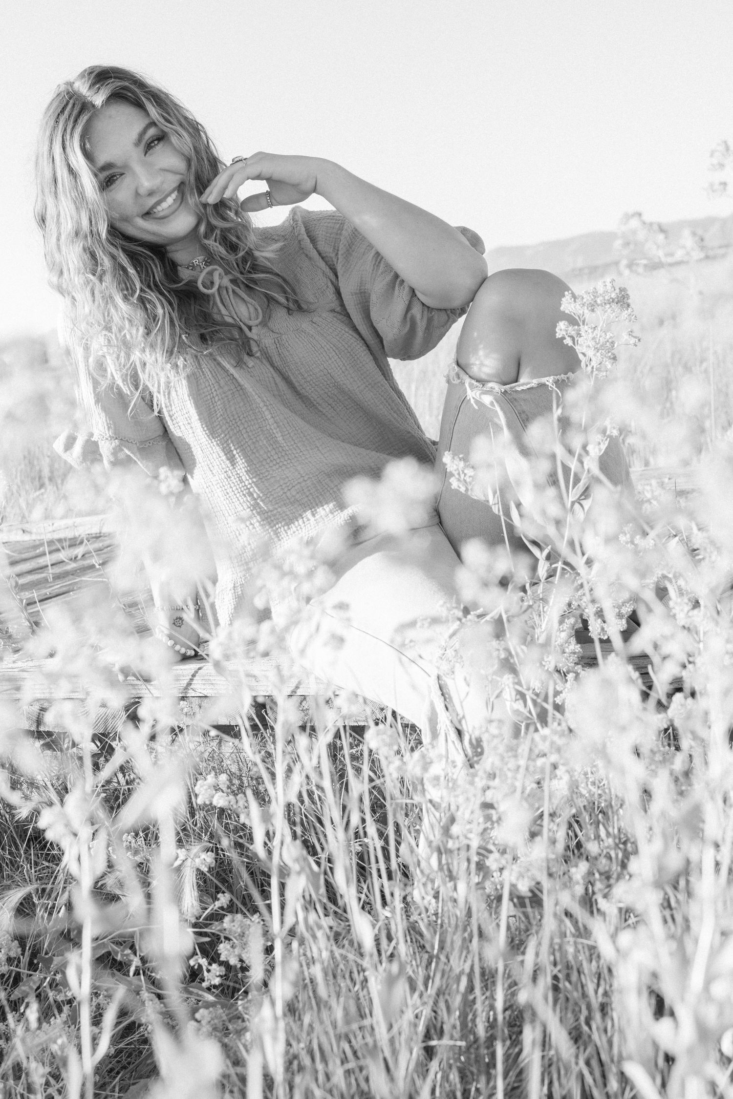 Monochromatic portraits of a woman posing in a field of white flowers on a bright sunny day.