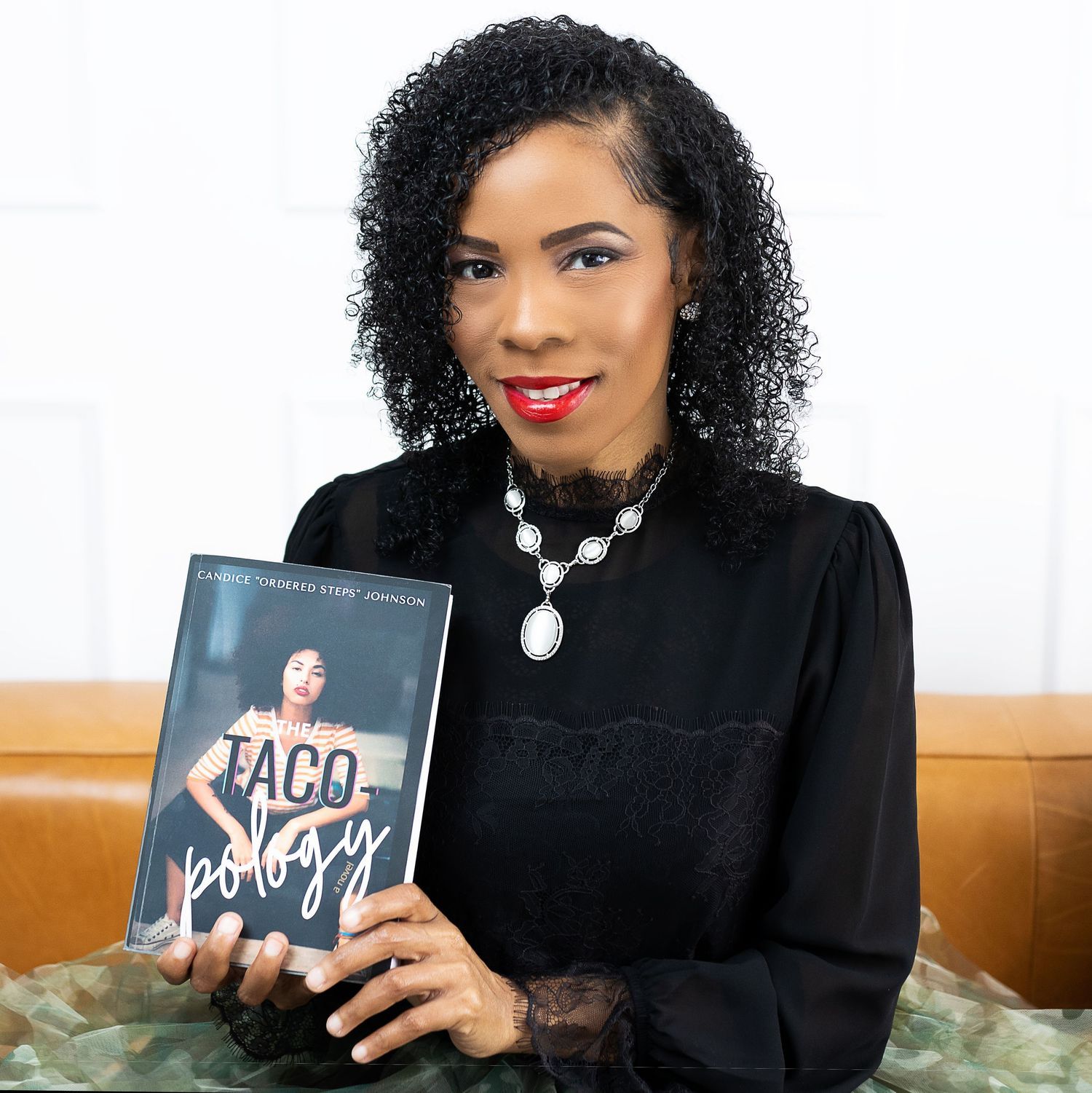 Professional author photo showing person in black dress holding their published book.