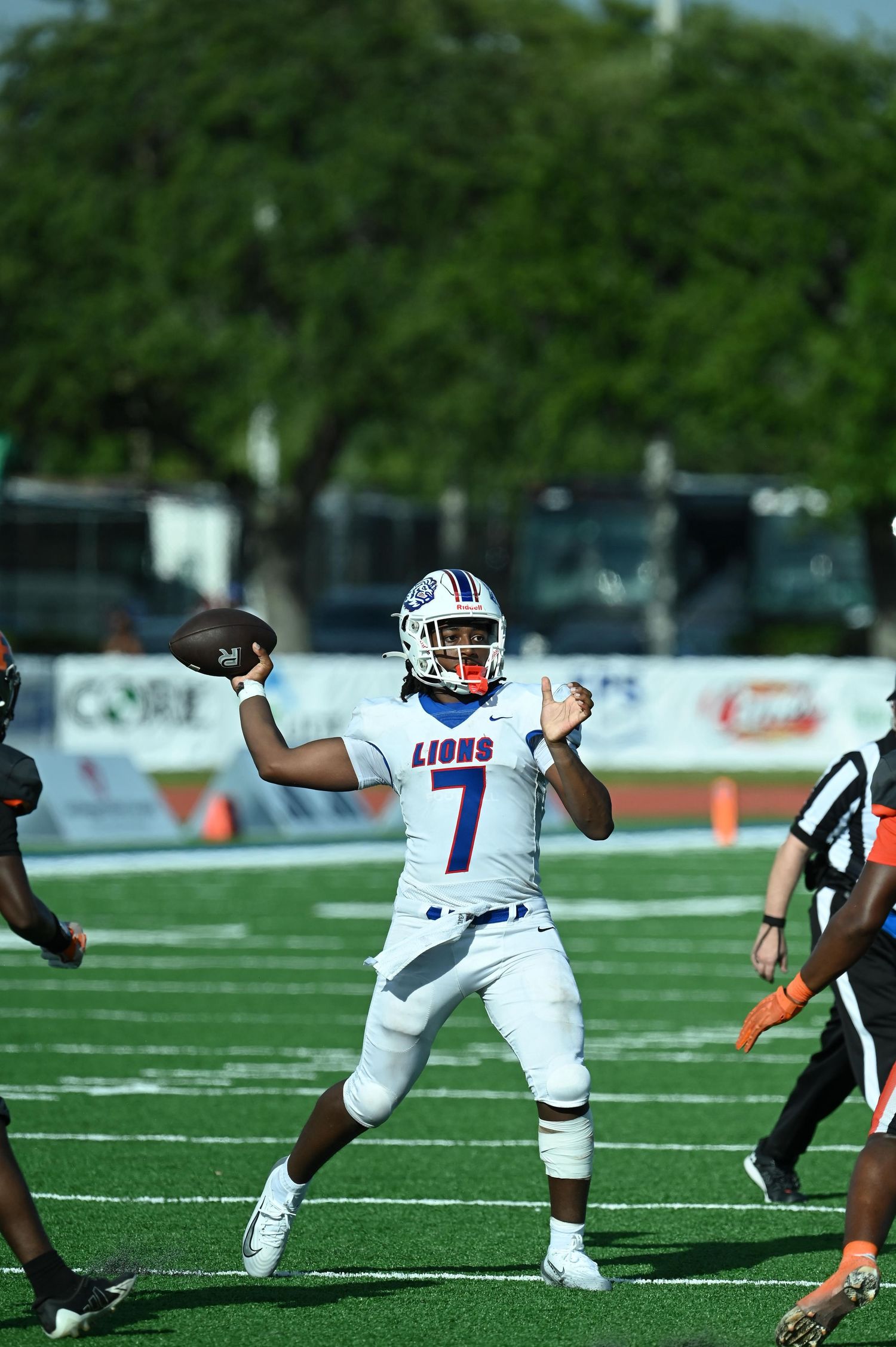 Lions #7 quarterback throws a pass during a high school football game on a green turf field.