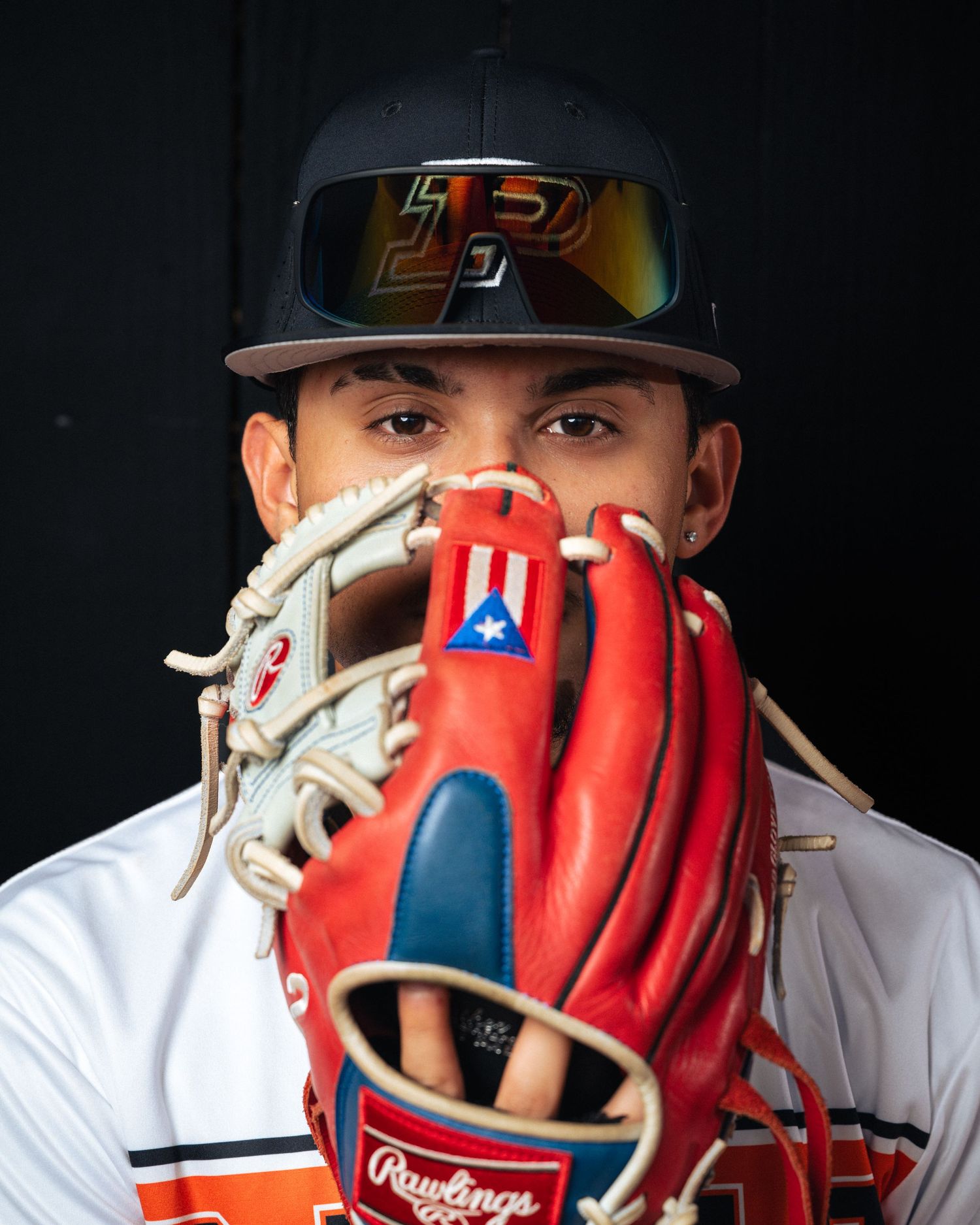 Close-up of a baseball player in South Florida holding a red and white glove over face, showcasing focus and determination.