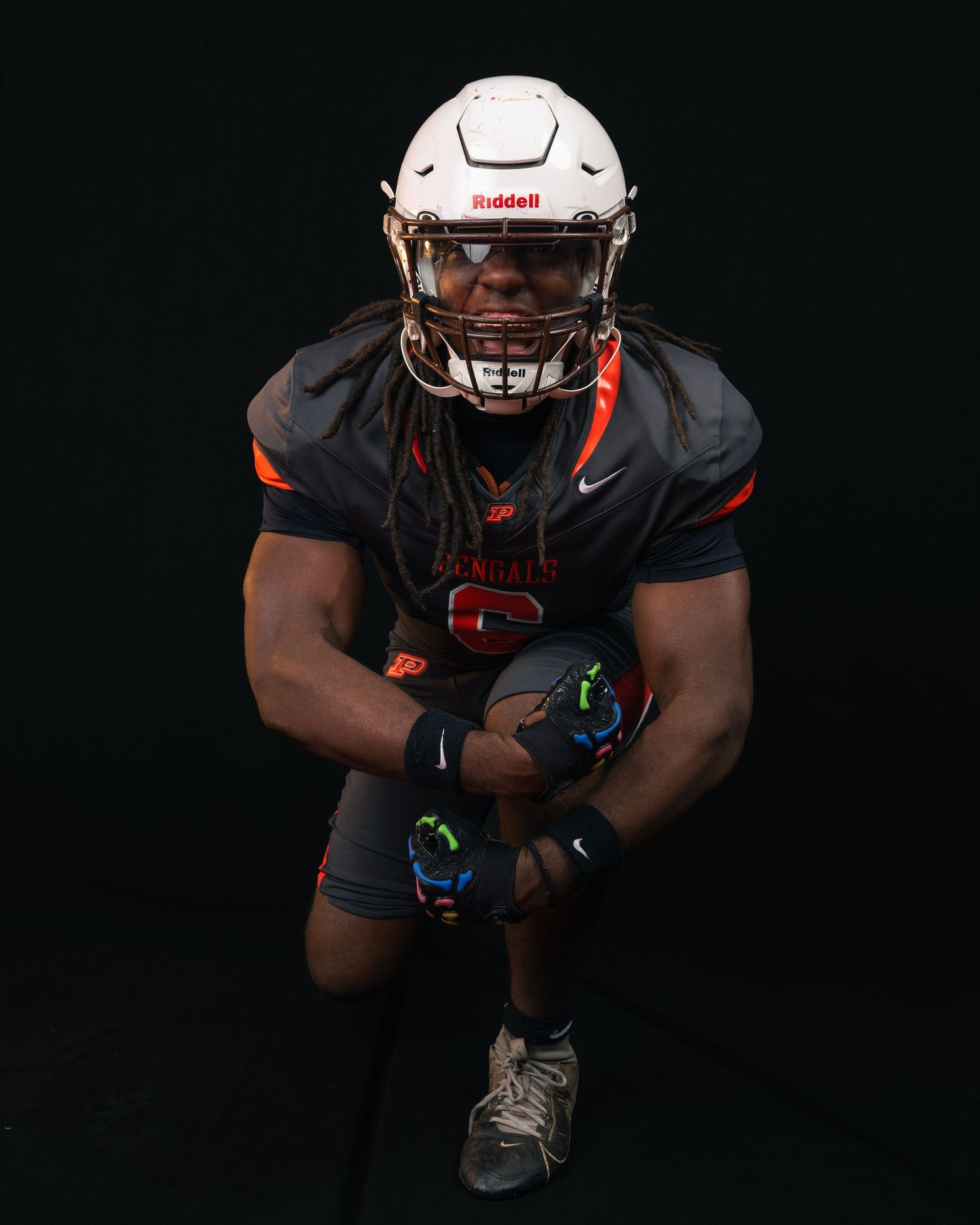 Bengals football player number 6 with dreadlocks crouching with ball in gray and orange Nike uniform.