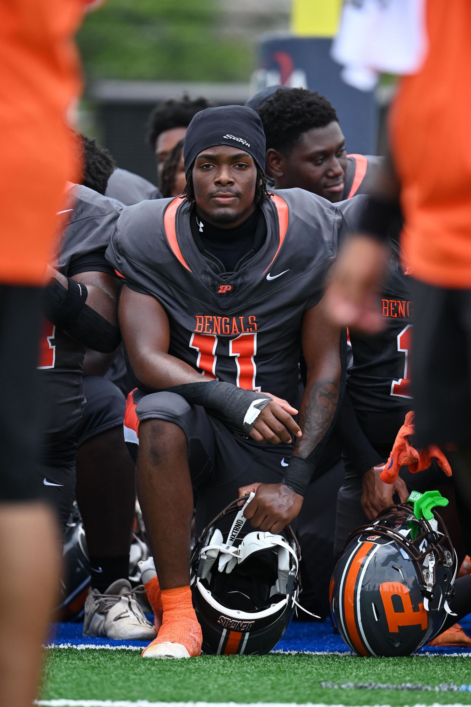 Bengals football player number 11 sitting on sideline bench holding helmet during a game.