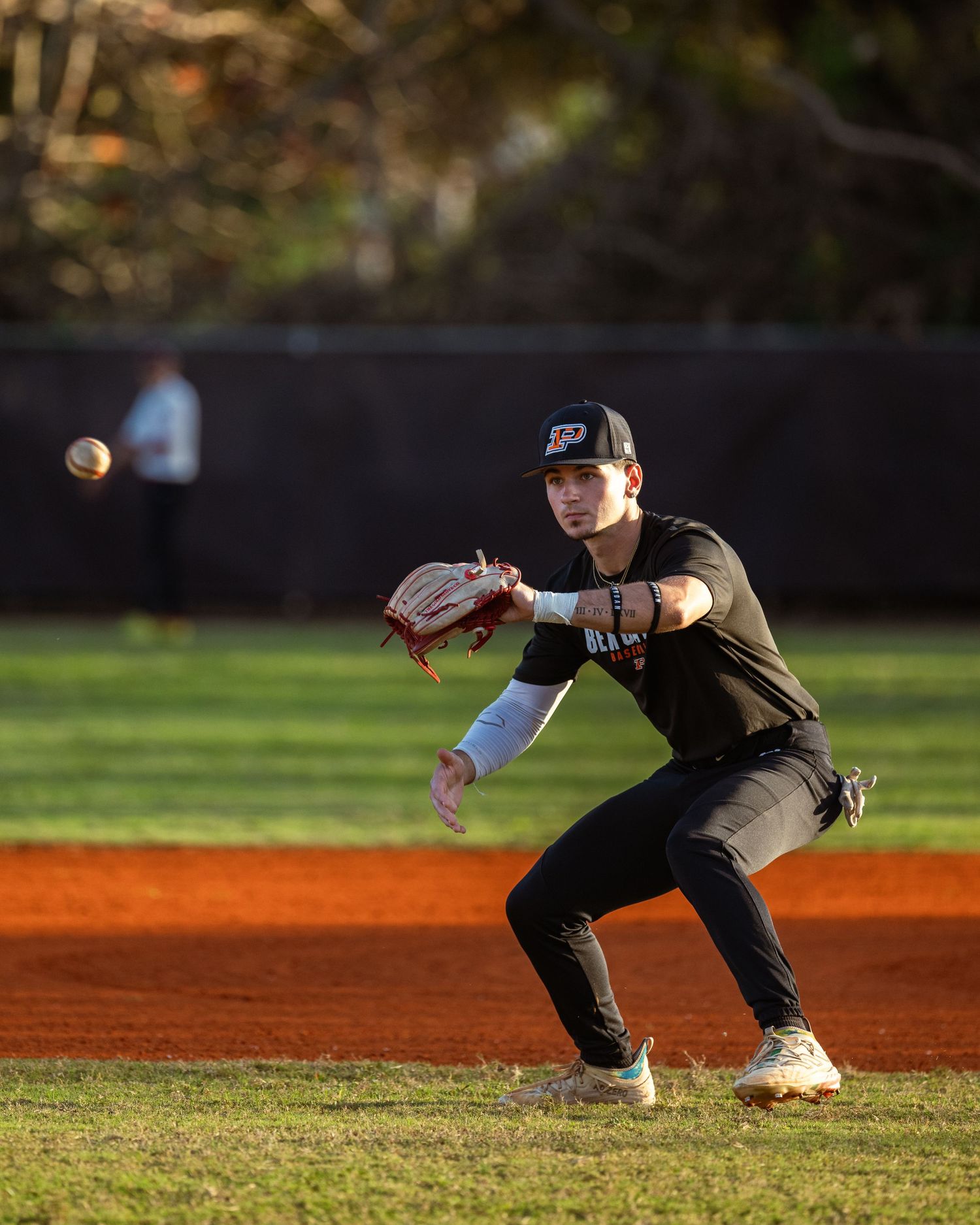 Athlete fields a throw on baseball infield in Sunrise, FL, during golden hour, showcasing defensive skills.