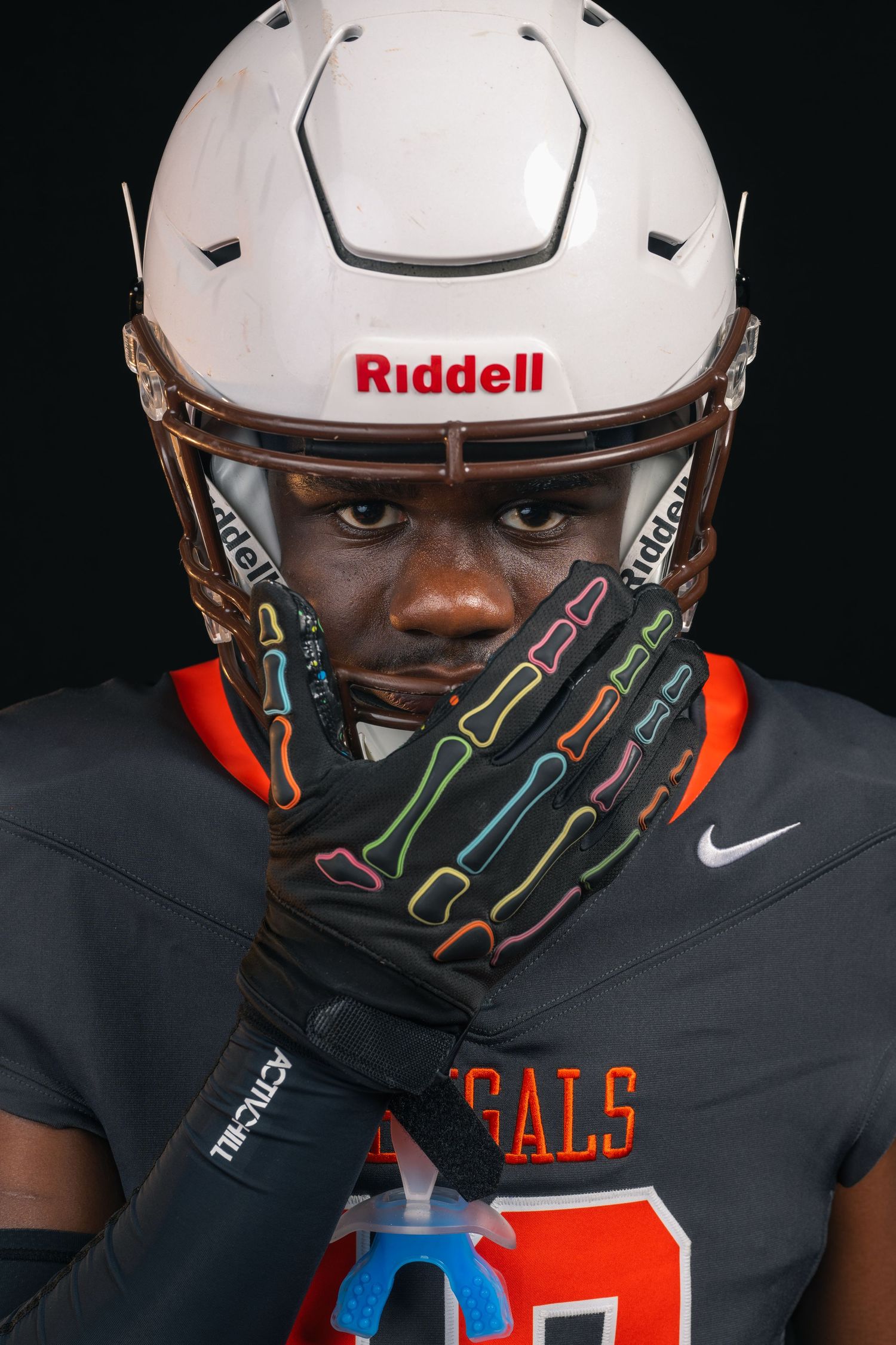 Bengals football player in white Riddell helmet and skeleton gloves covering mouth, intense game-ready portrait.