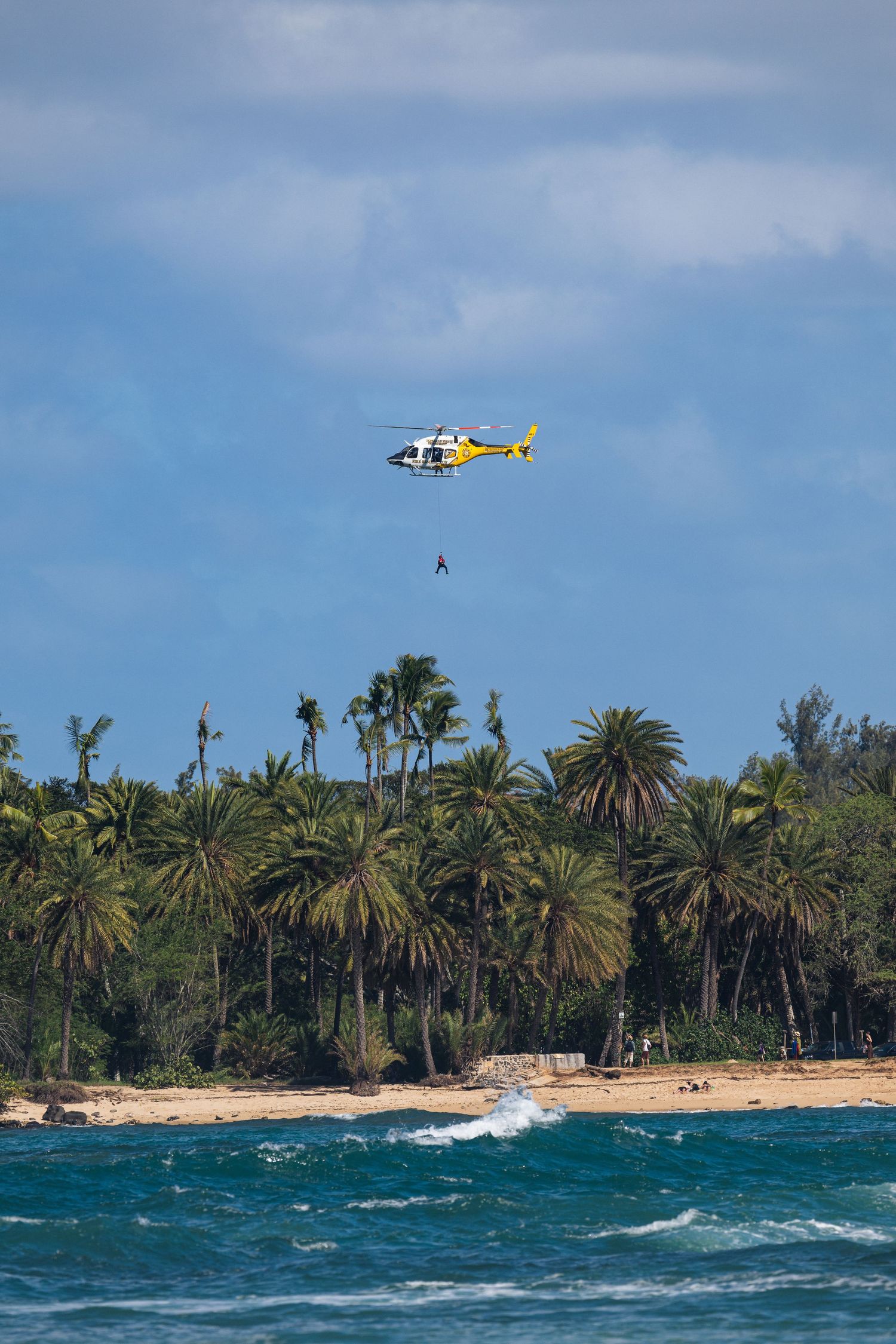 Rescue person hangs from rescue helicopter on the North Shore of Oahu. Taken by Fort Lauderdale photographer.