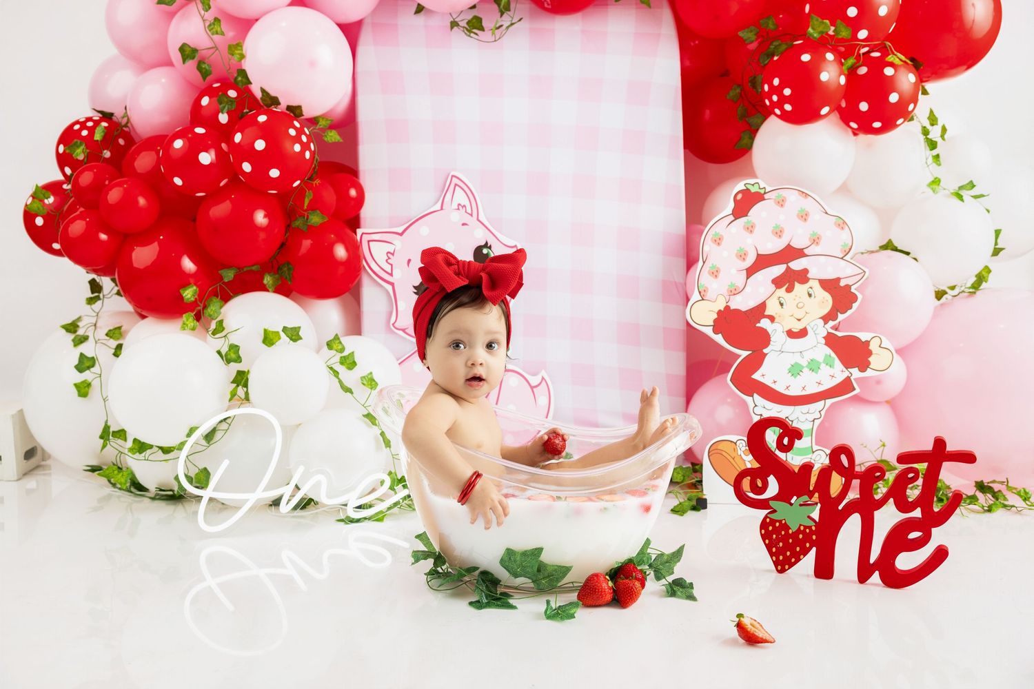 Pink and red Valentine's day photography setup with hearts, flowers, and cherries against a white background.