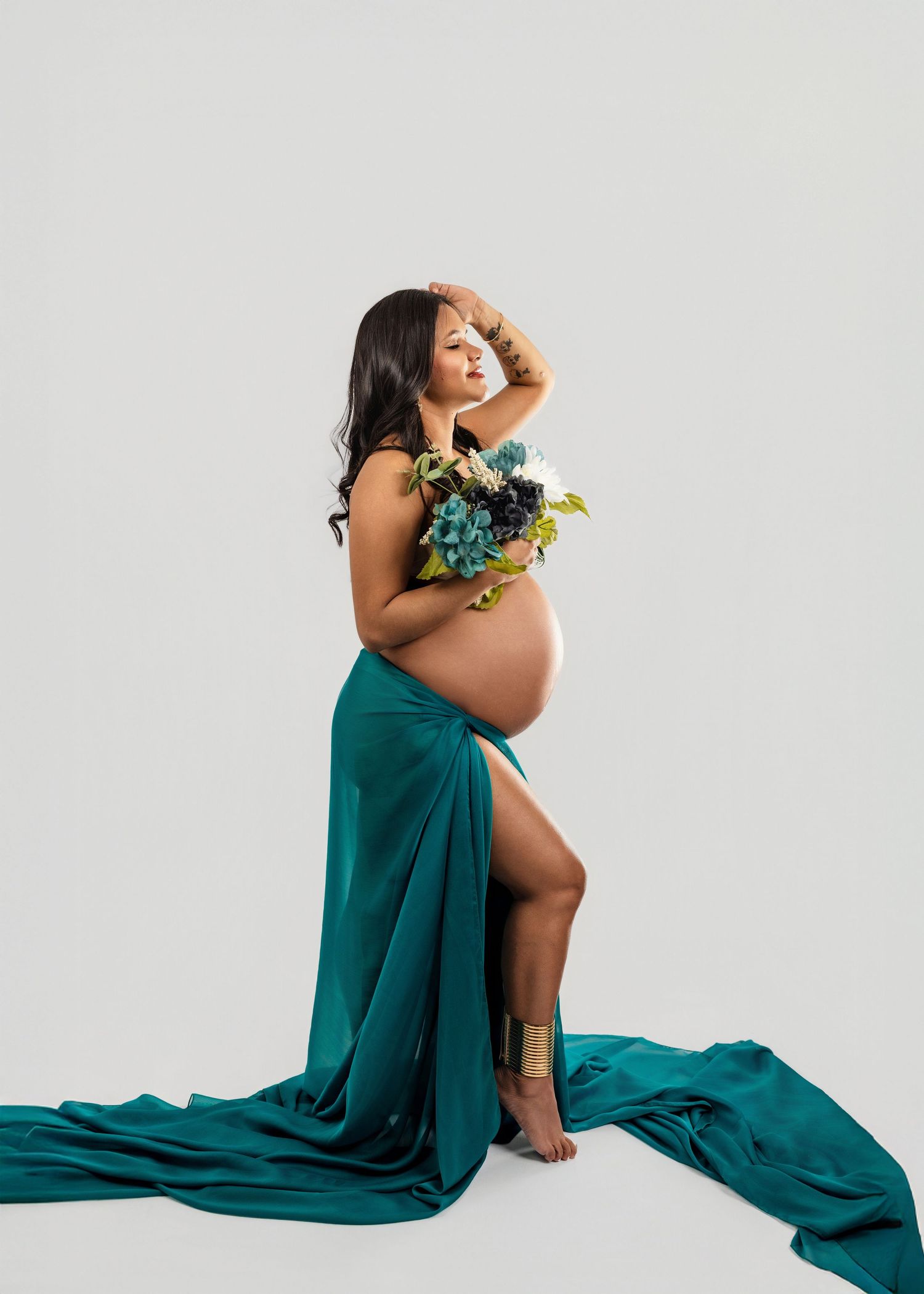 A series of artistic maternity portraits showing a woman in a flowing teal gown against a white backdrop.