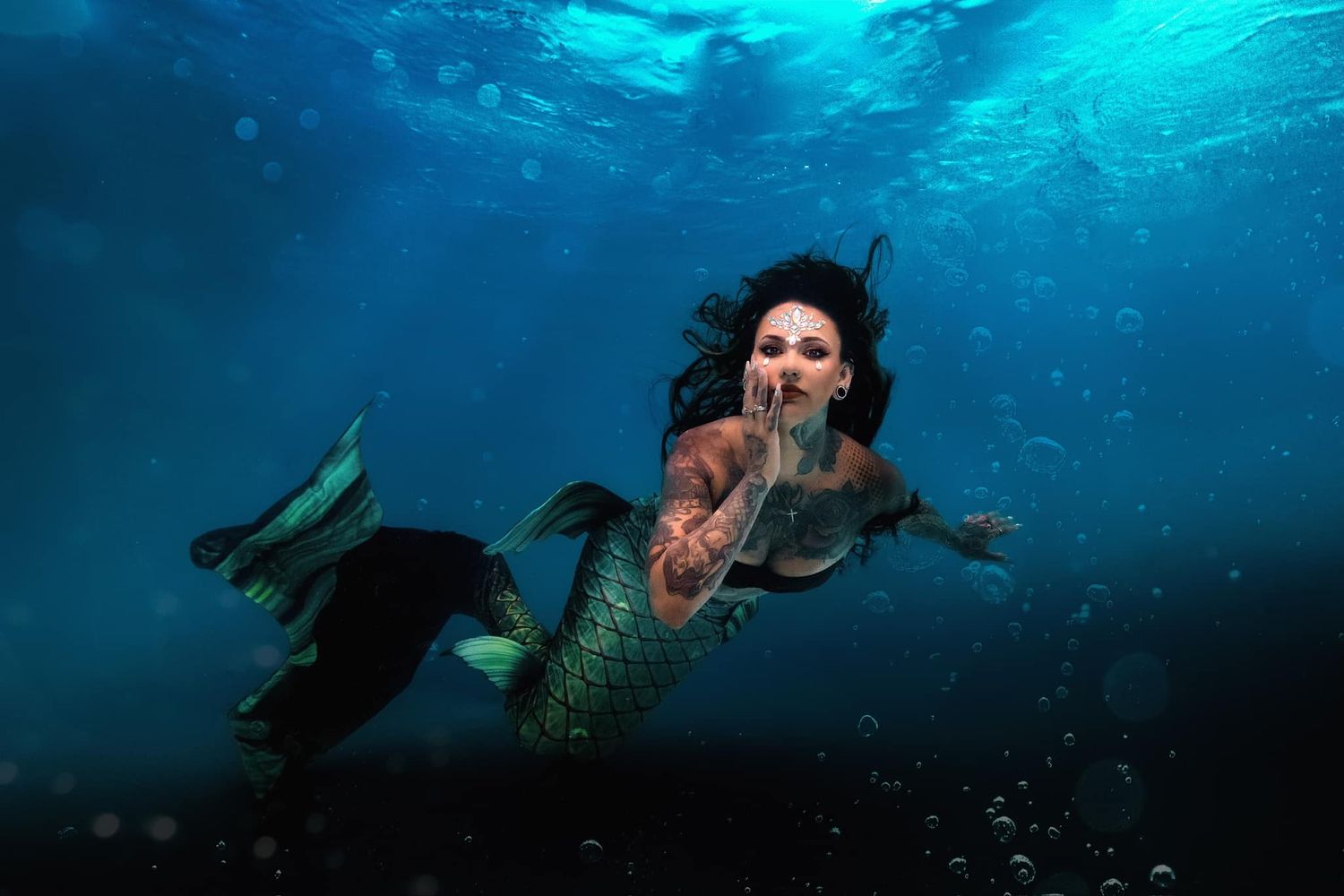 A magical underwater scene shows a mythical mermaid with long dark hair swimming beneath turquoise waters.