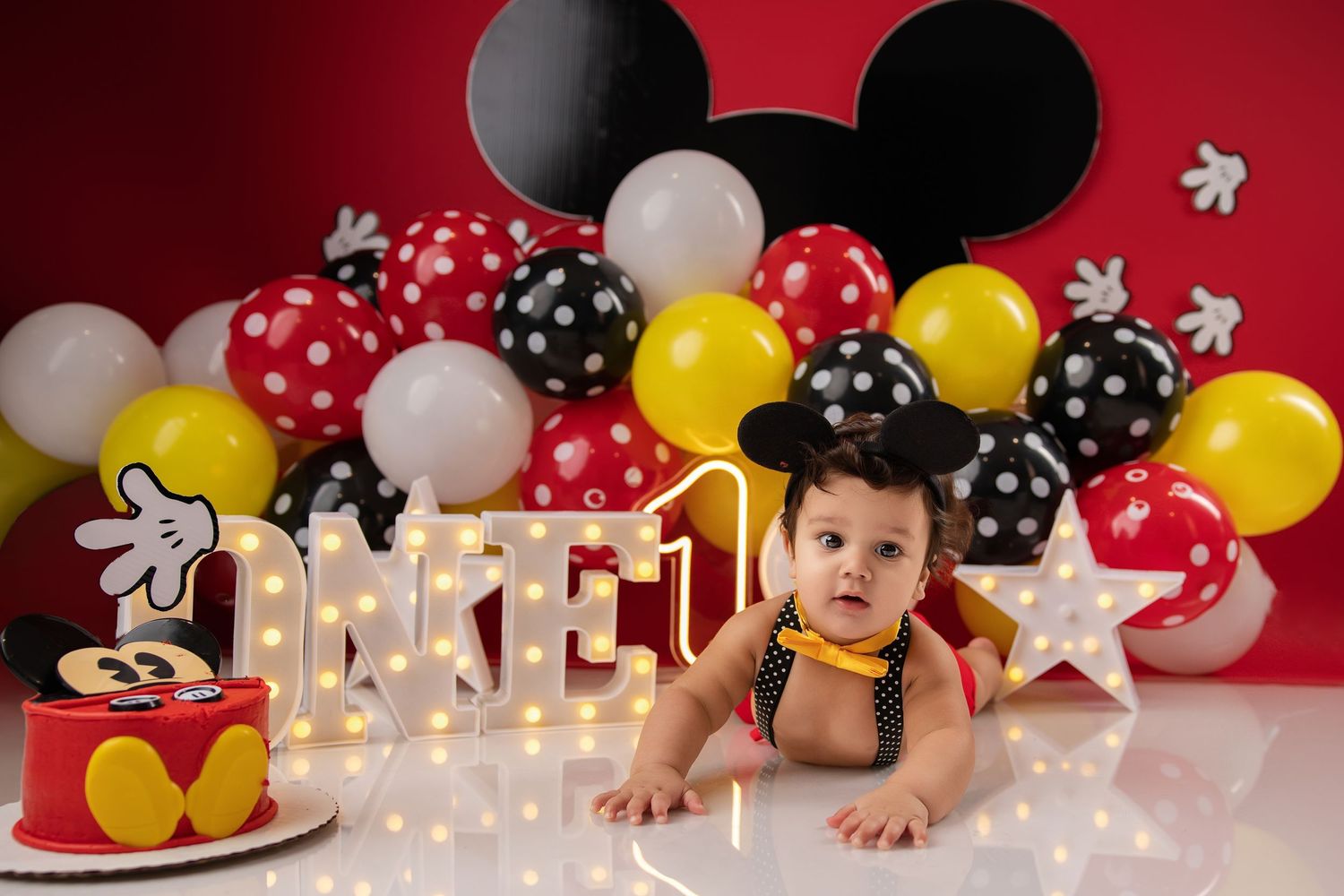 Baby's first birthday Mickey Mouse themed photo with balloons, cake, and marquee letters spelling ME 1.