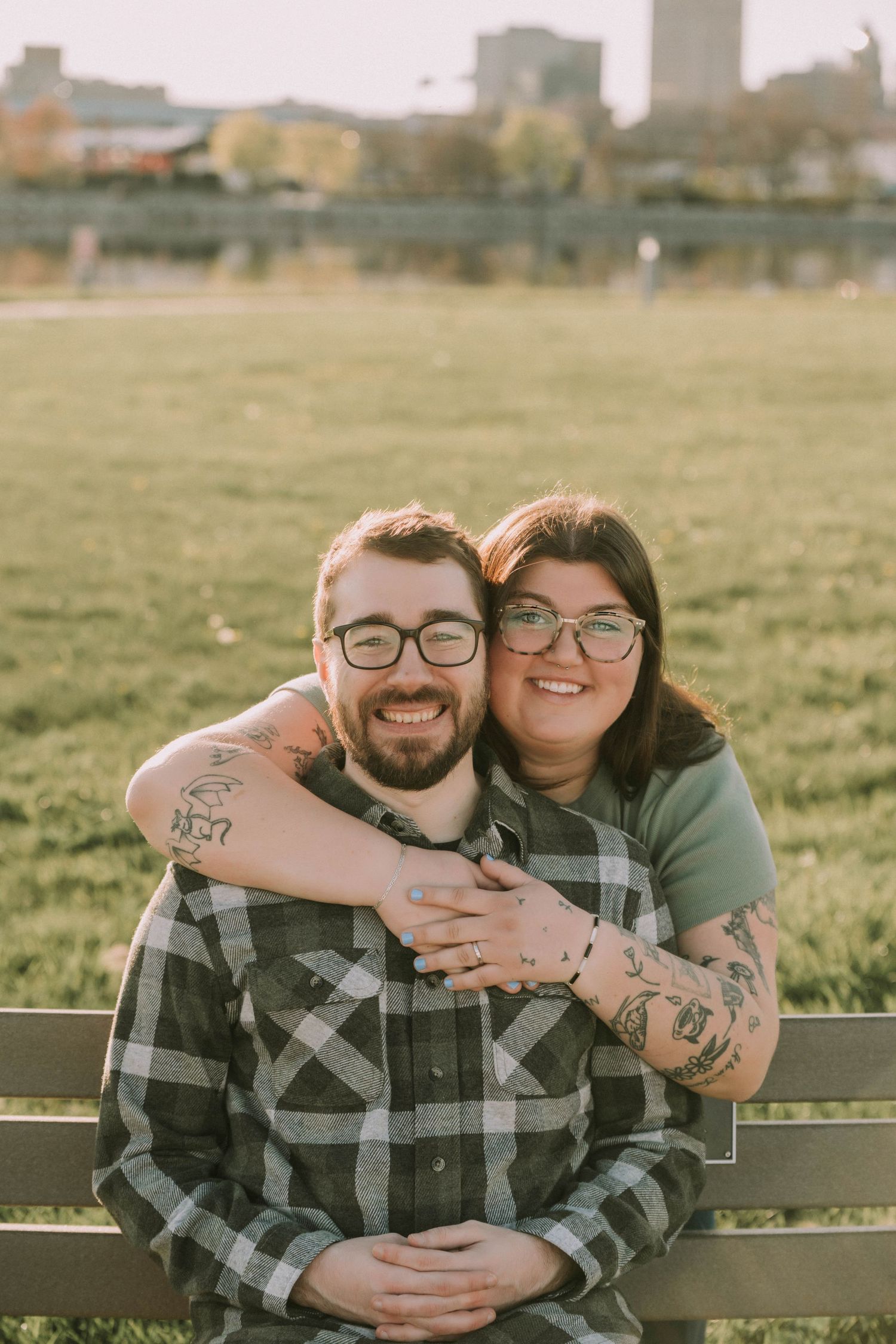 Couple sharing intimate moments on wooden bench in golden sunlit field.