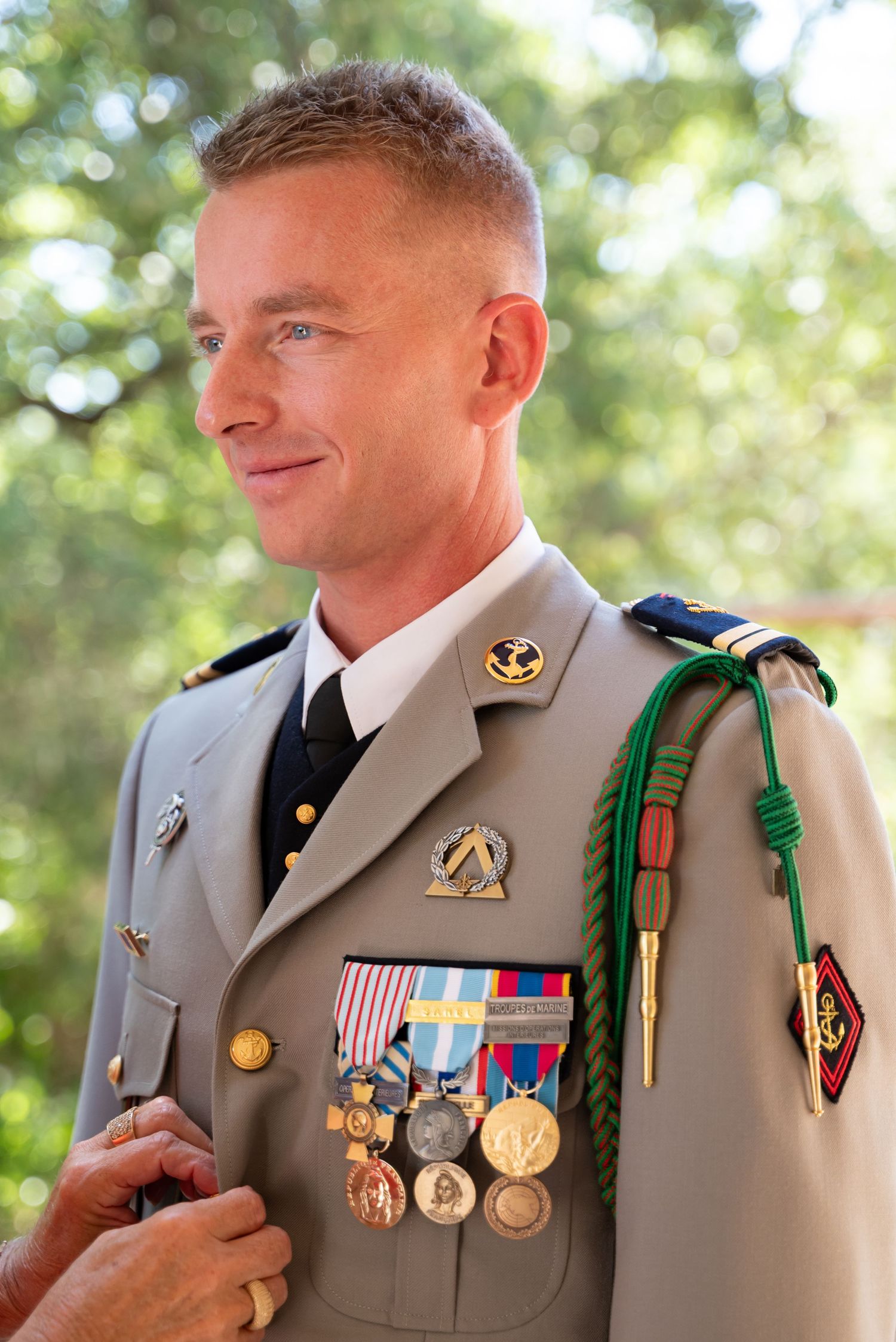 Military service member in dress uniform displaying medals and decorations at formal event.