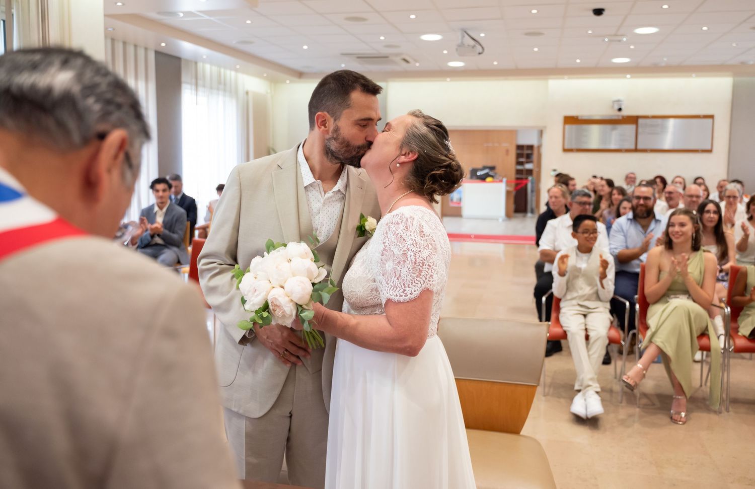Couple sharing a romantic moment during their wedding ceremony in a bright hall.