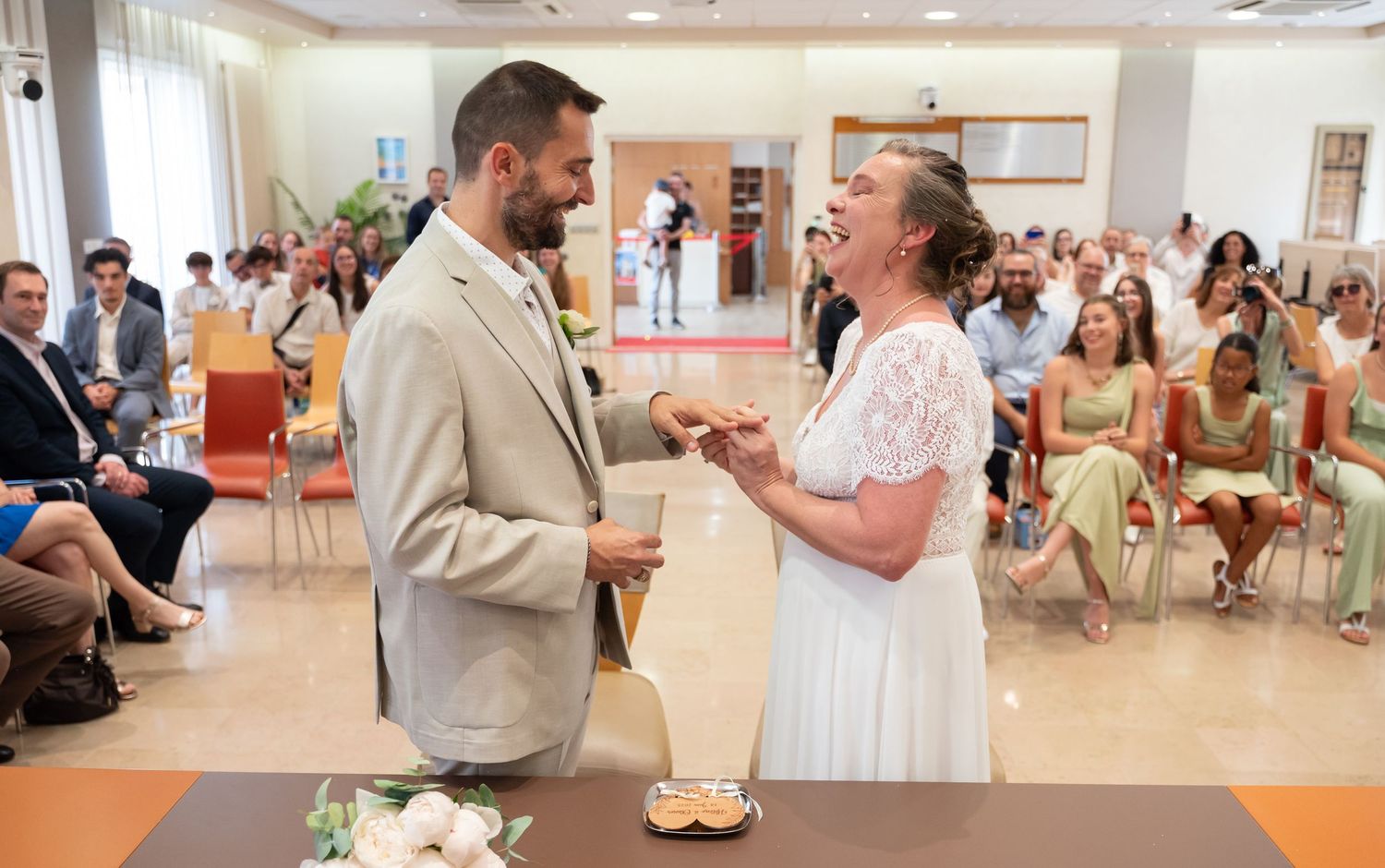 Couple exchanging rings during their wedding ceremony in front of seated guests.