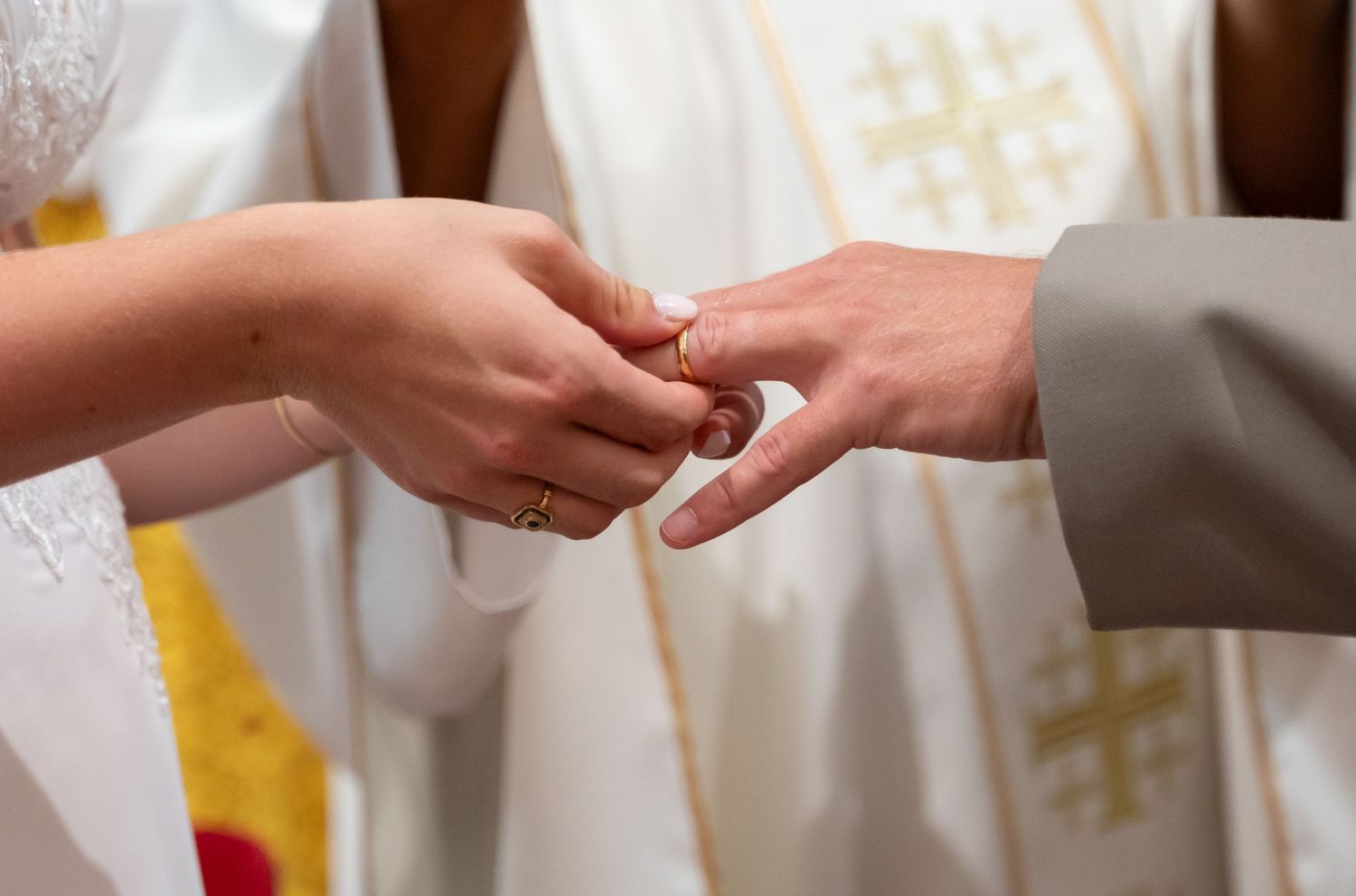 Close up of hands exchanging wedding rings during traditional church ceremony.
