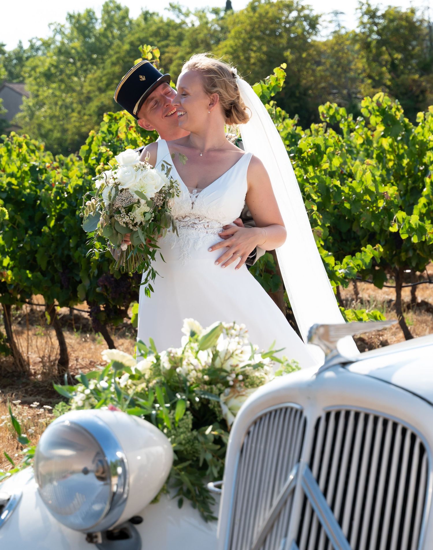 Elegant wedding scene featuring a classic white vintage car among lush vineyard rows.