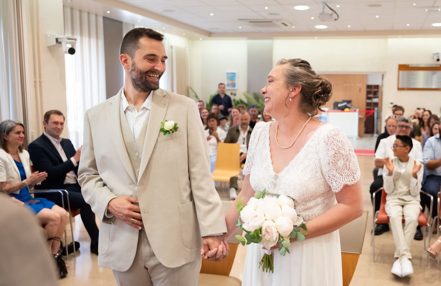 Couple stands together during intimate wedding ceremony in bright indoor venue.