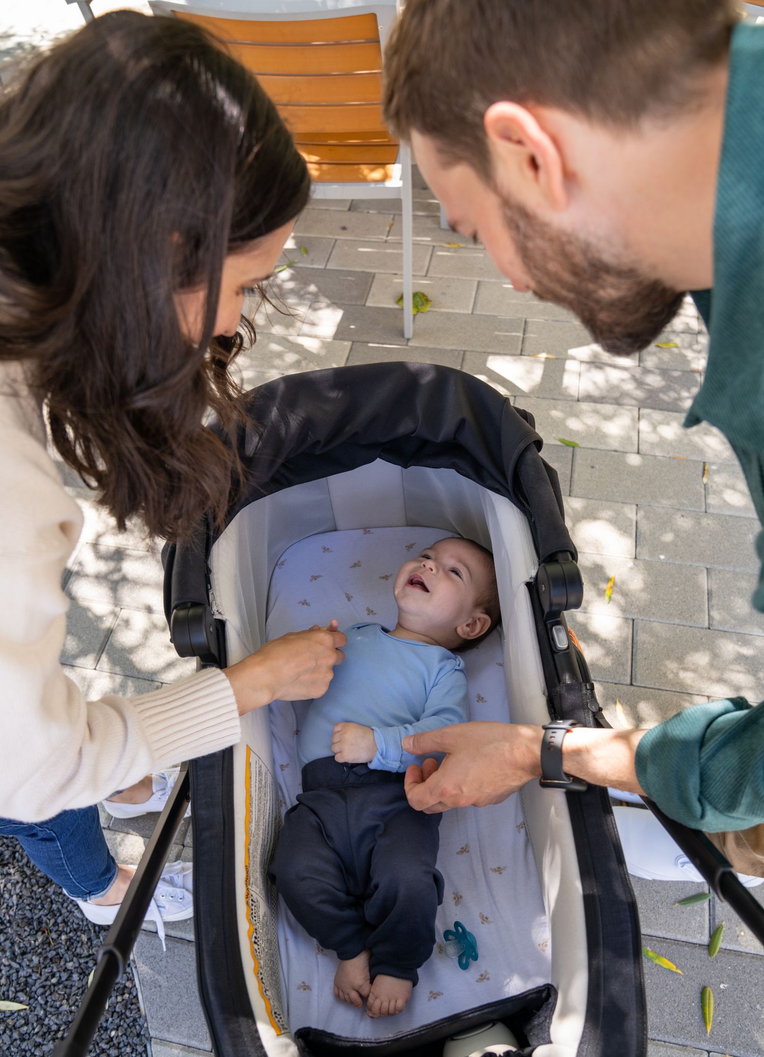 Medical professionals perform an examination on a small infant lying on a blue exam table outdoors.