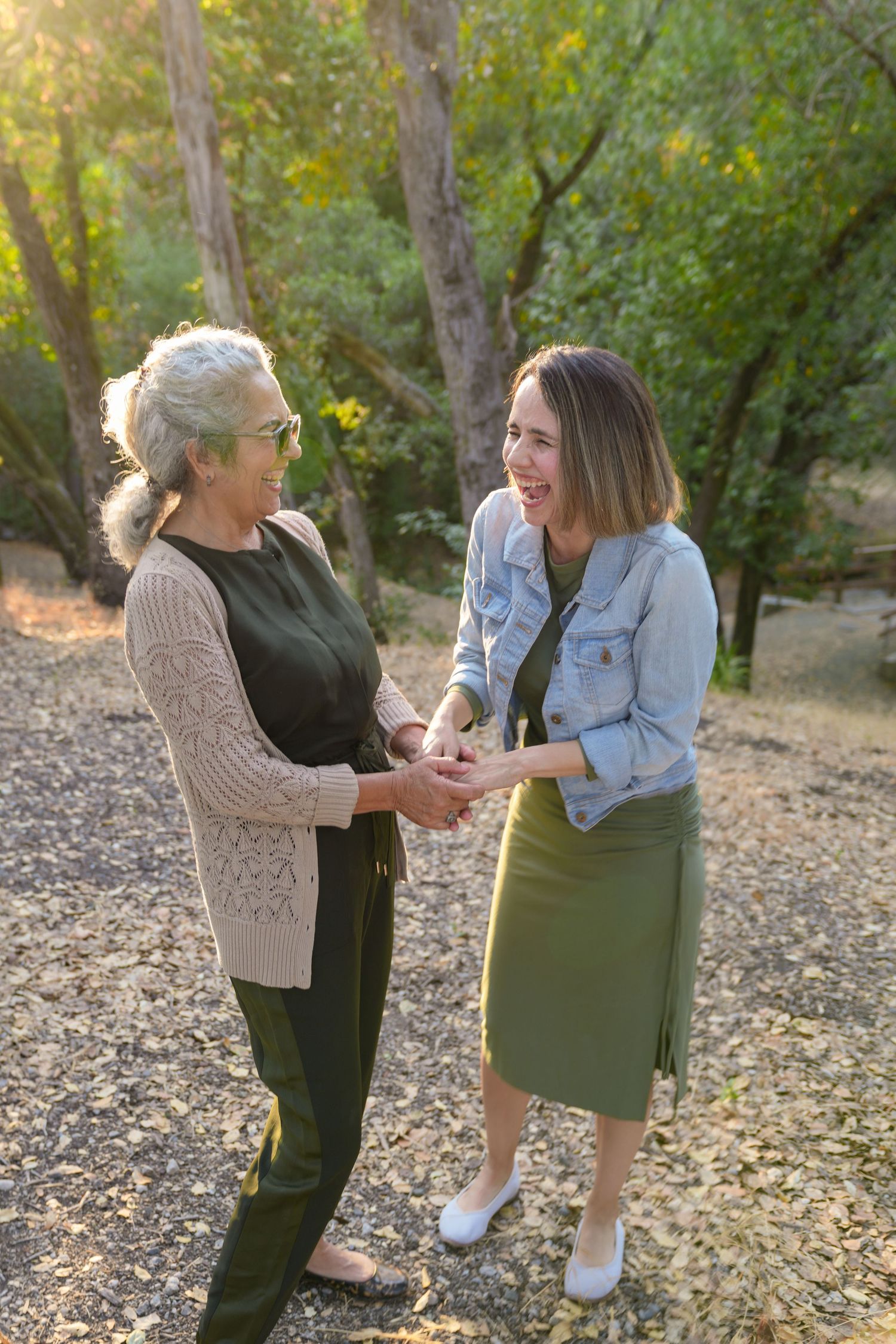Two people share playful moments outdoors surrounded by fallen autumn leaves.