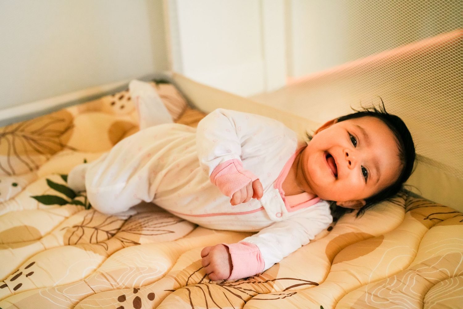 Infant in light clothing exploring floral print bedding.