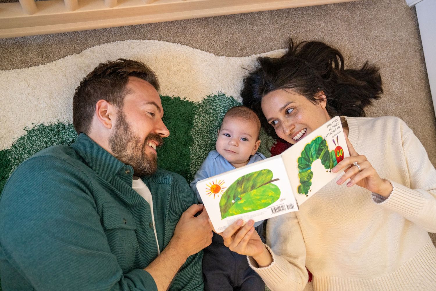 A family reads a children's book together while relaxing on a couch.