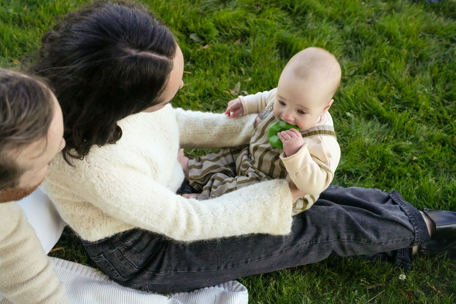 A gentle interaction on grass while wearing cozy sweaters.