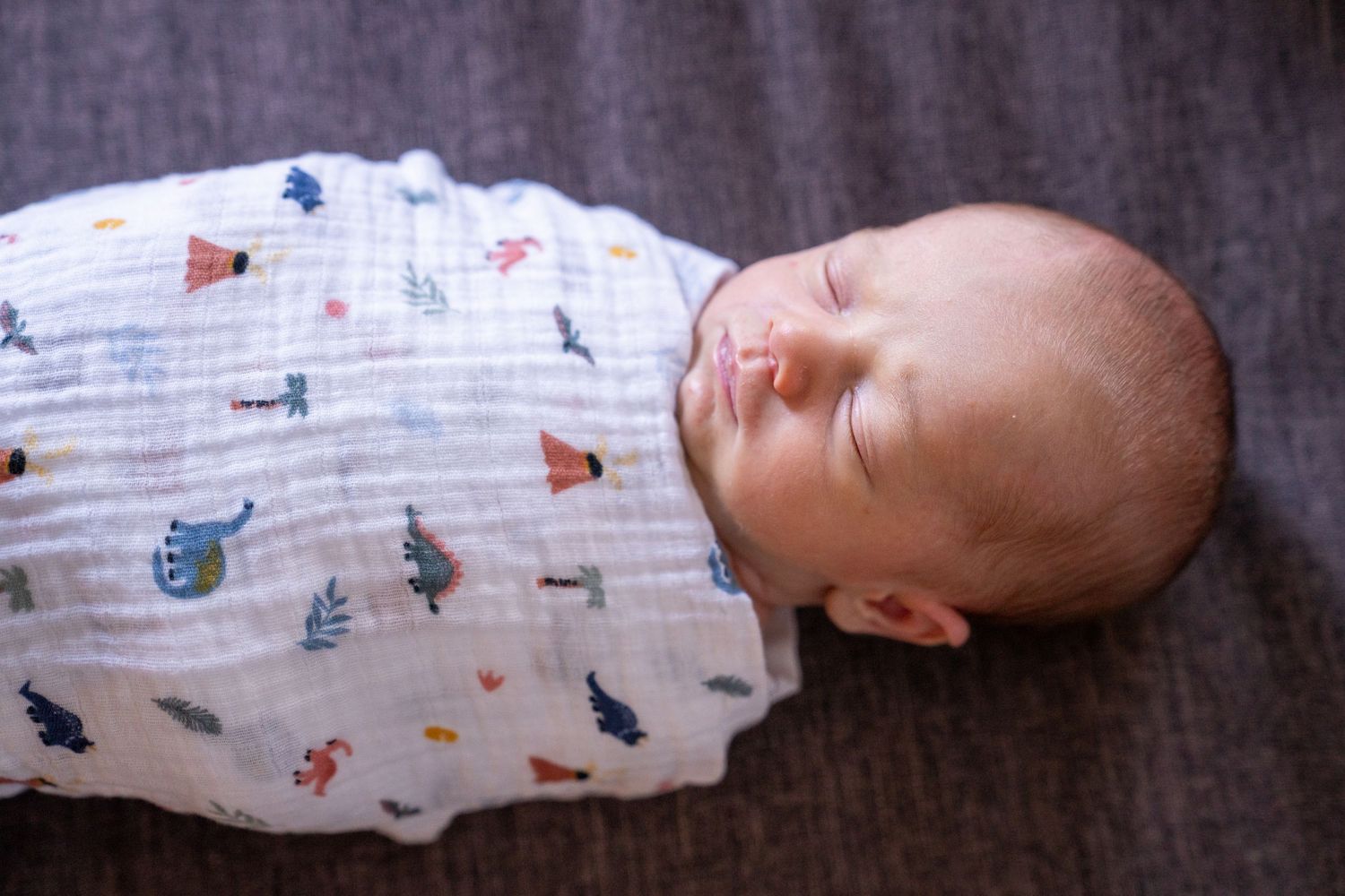 A series of five connected photos showing a sleeping baby swaddled in white cloth with colorful patterns.