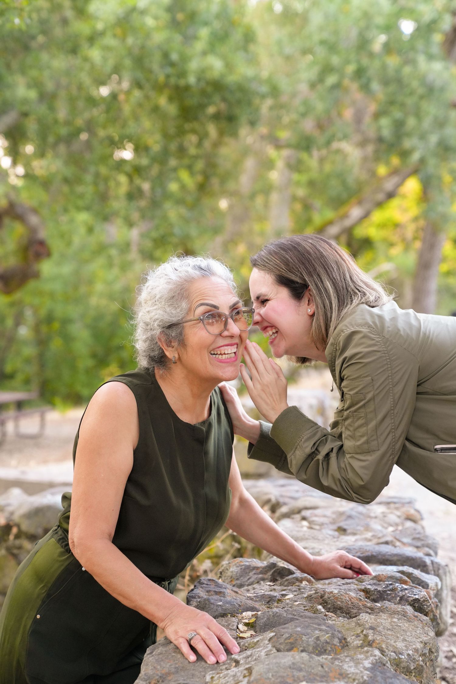 Daughter telling mother a secret in candid portrait, sharing a playful moment together in a natural setting.