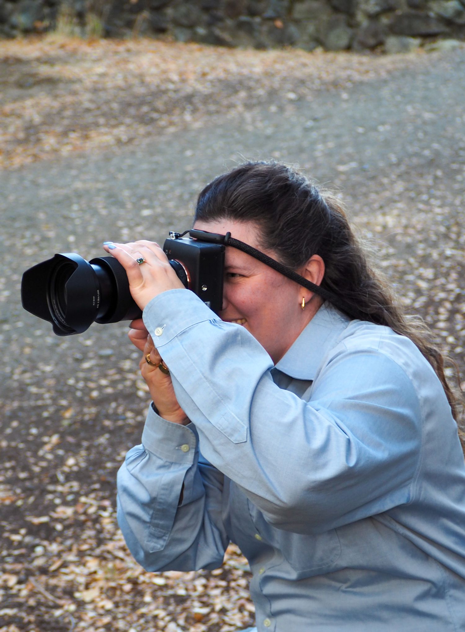 Photographer taking photos with a telephoto lens while wearing a light colored shirt.