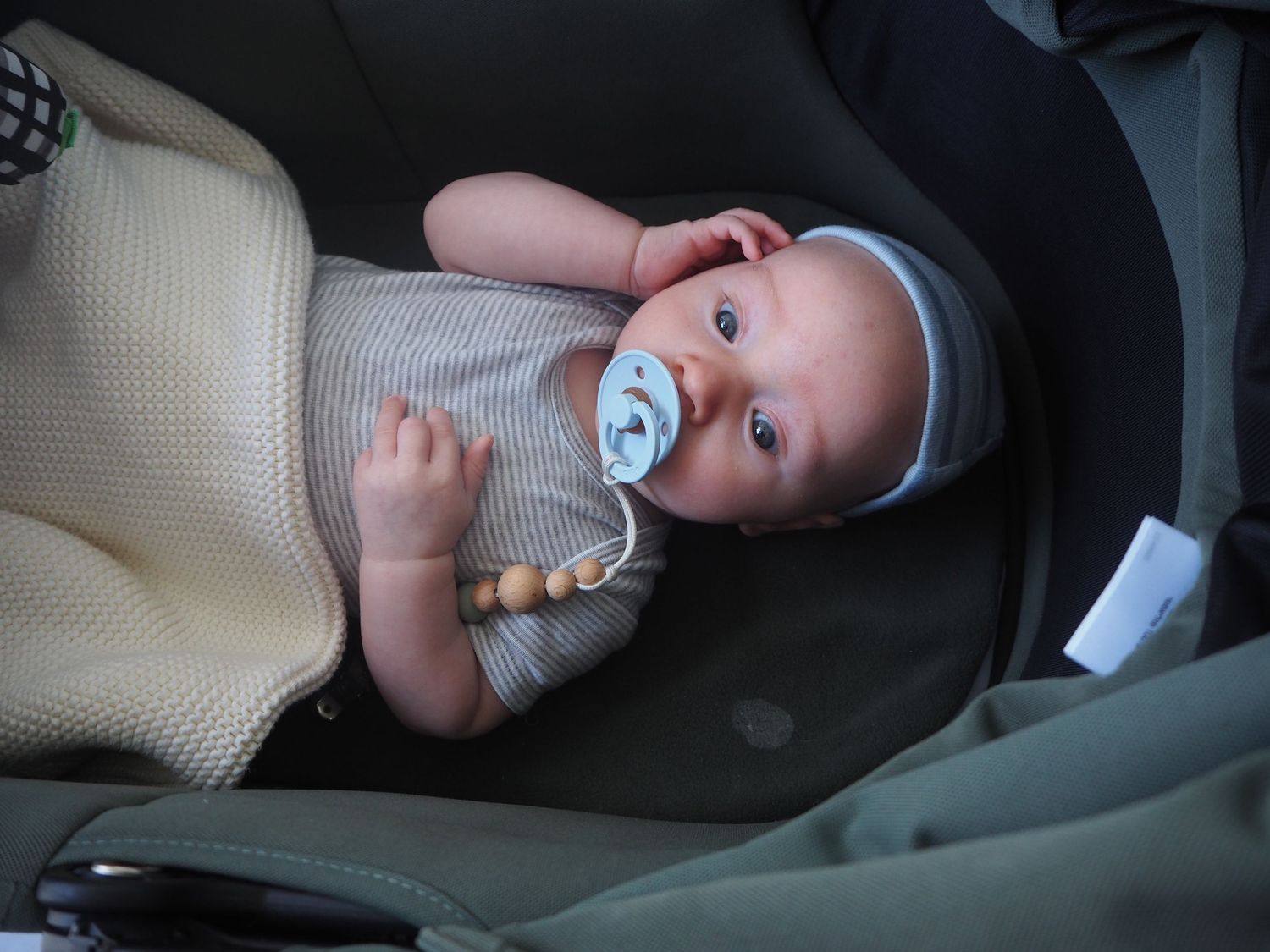 A small baby in gray clothing laying on a cushioned surface.