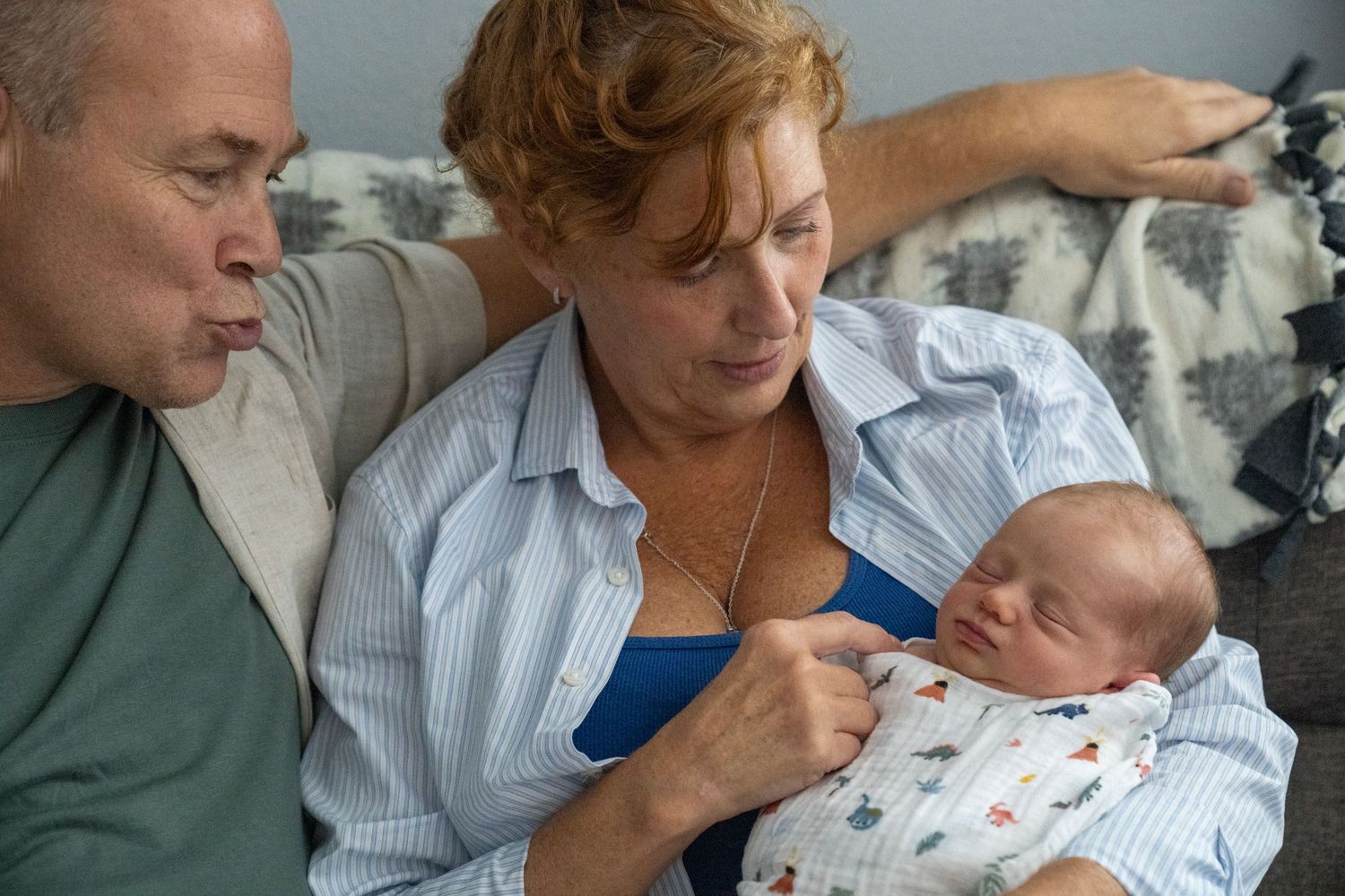 A couple shares a tender moment while lying down with their newborn baby.