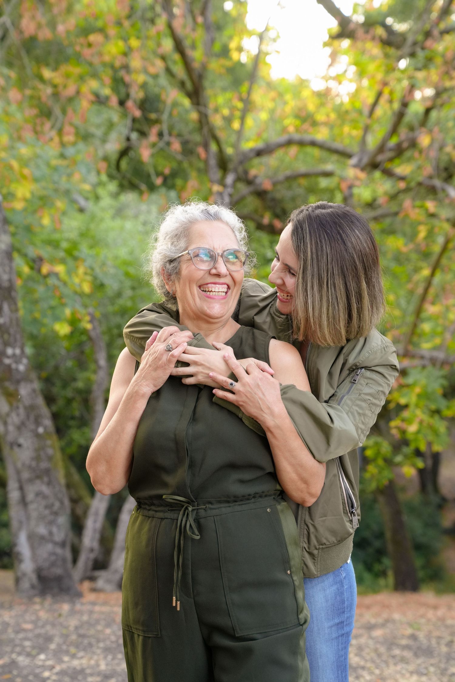 Mother and daughter share affectionate moments while embracing in an outdoor autumn setting.