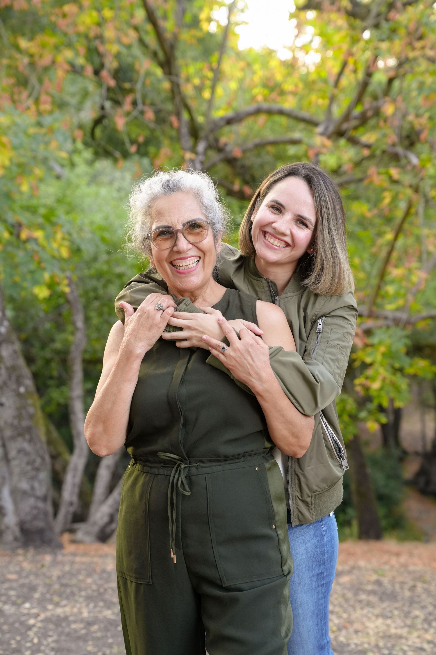Two people sharing a joyful moment together outdoors among autumn trees and fallen leaves.