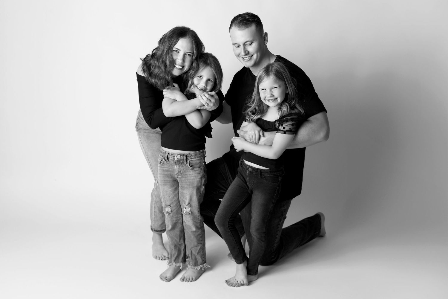 Parents hold kids and laugh at camera in black and white natural mini studio session Phoenix AZ