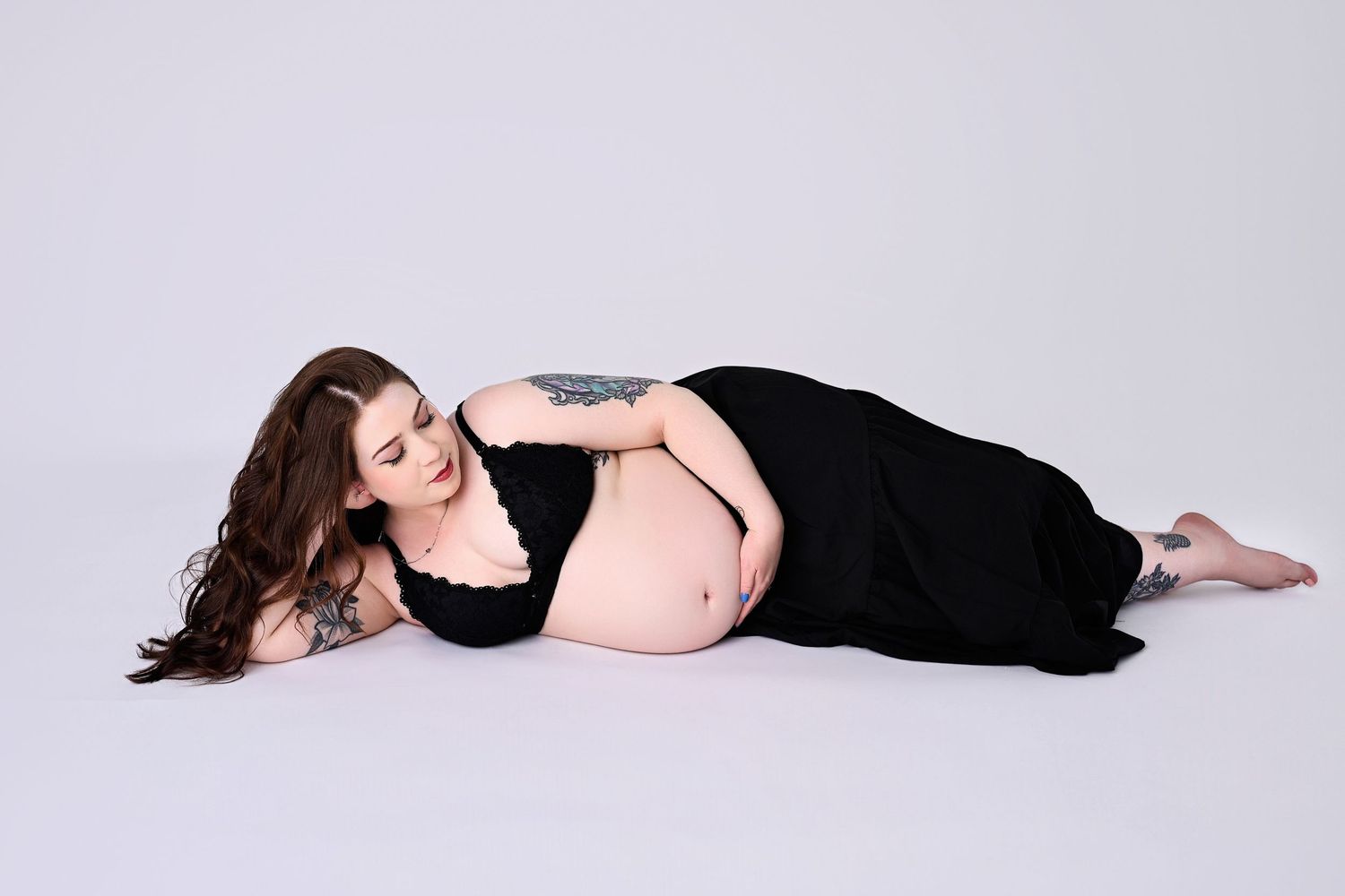 Pregnant Mother lays on her side lovingly gazing down her body and caressing her rounded belly