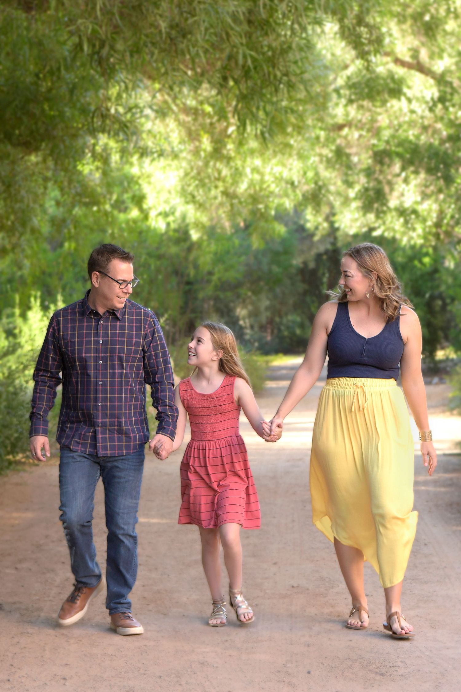 Parents holding hands with their children in a sunny park.