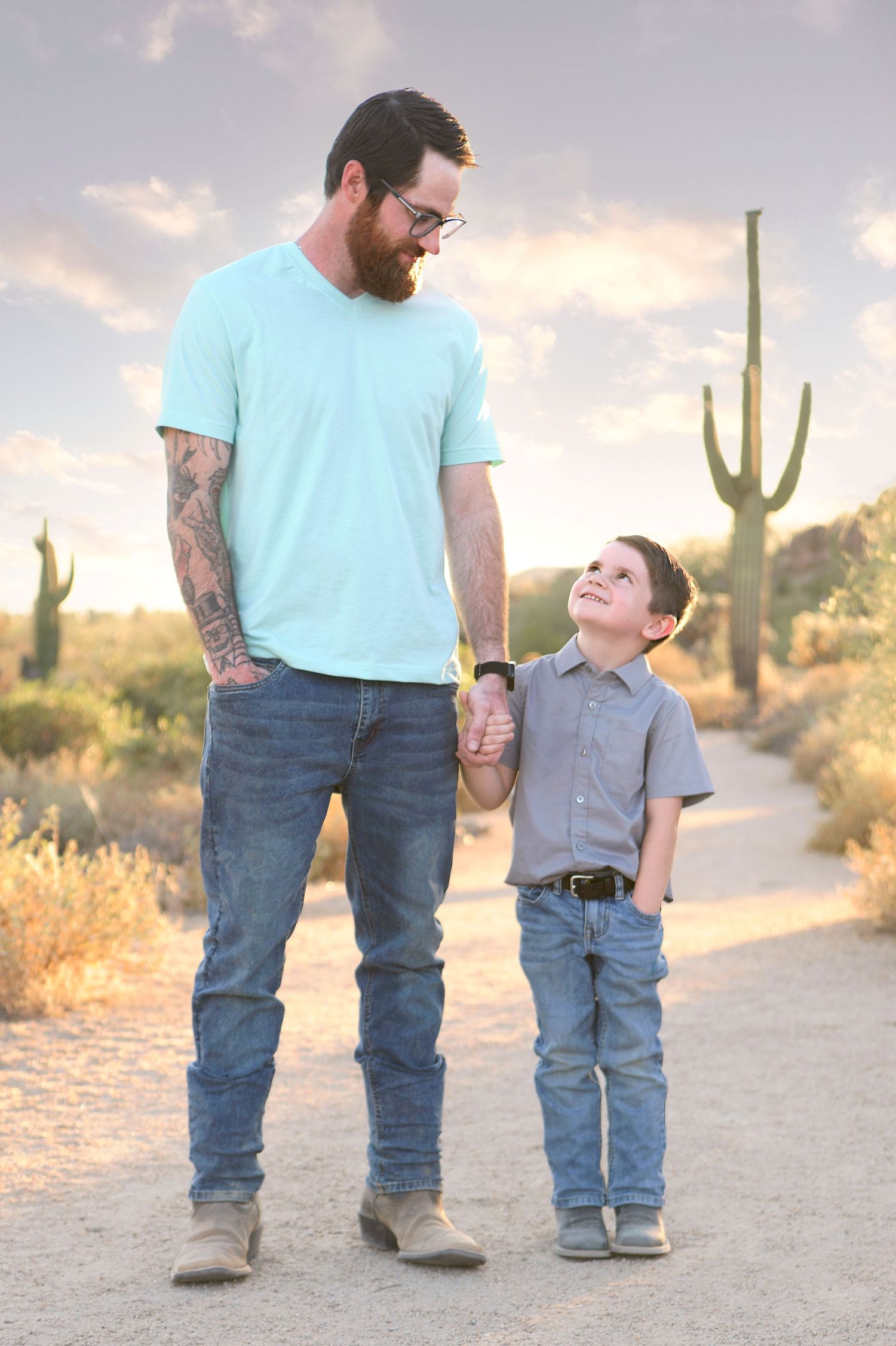 Rustic Arizona desert with large cactus. Young boy looks up to his Daddy on a cloudy day