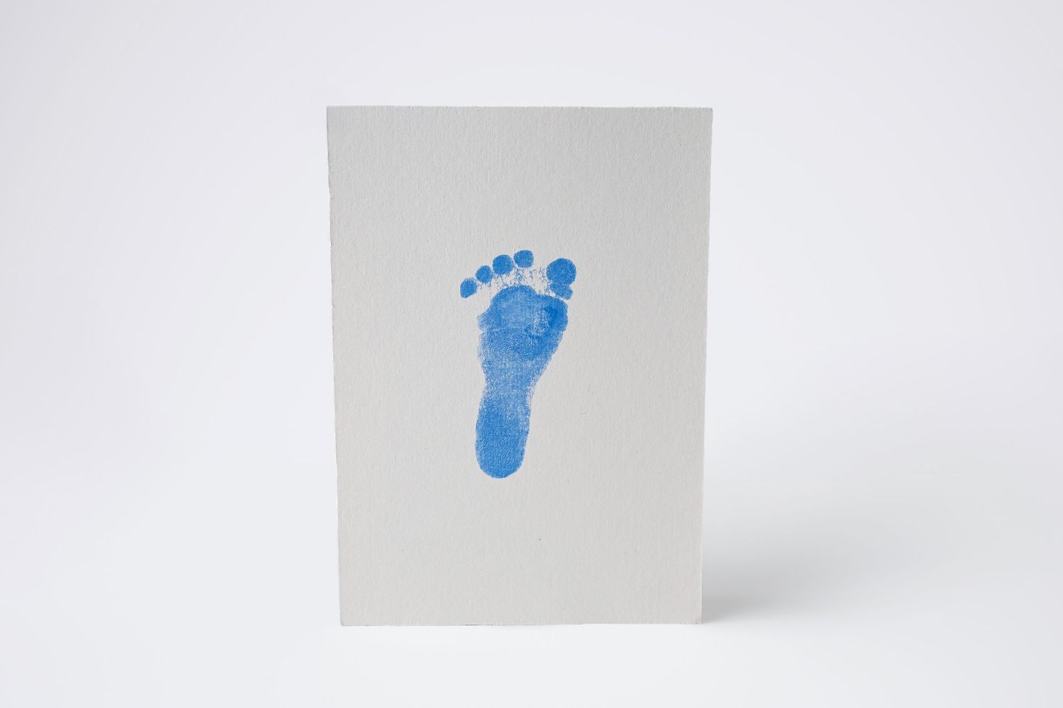 A blue baby's footprint on a piece of card stock. A handmade luxury newborn keepsake in Phoenix Arizona
