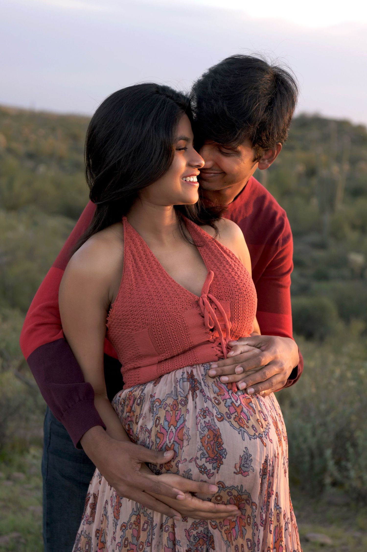 Pregnant couple is snuggling bathed in golden arizona sunset light