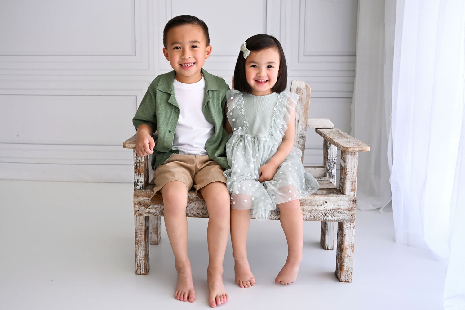 Siblings wearing matching outfits in a colorful studio.