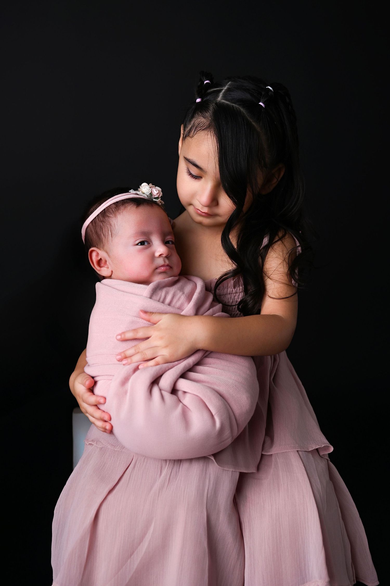 Big sister lovingly holds new baby sister in her arms
