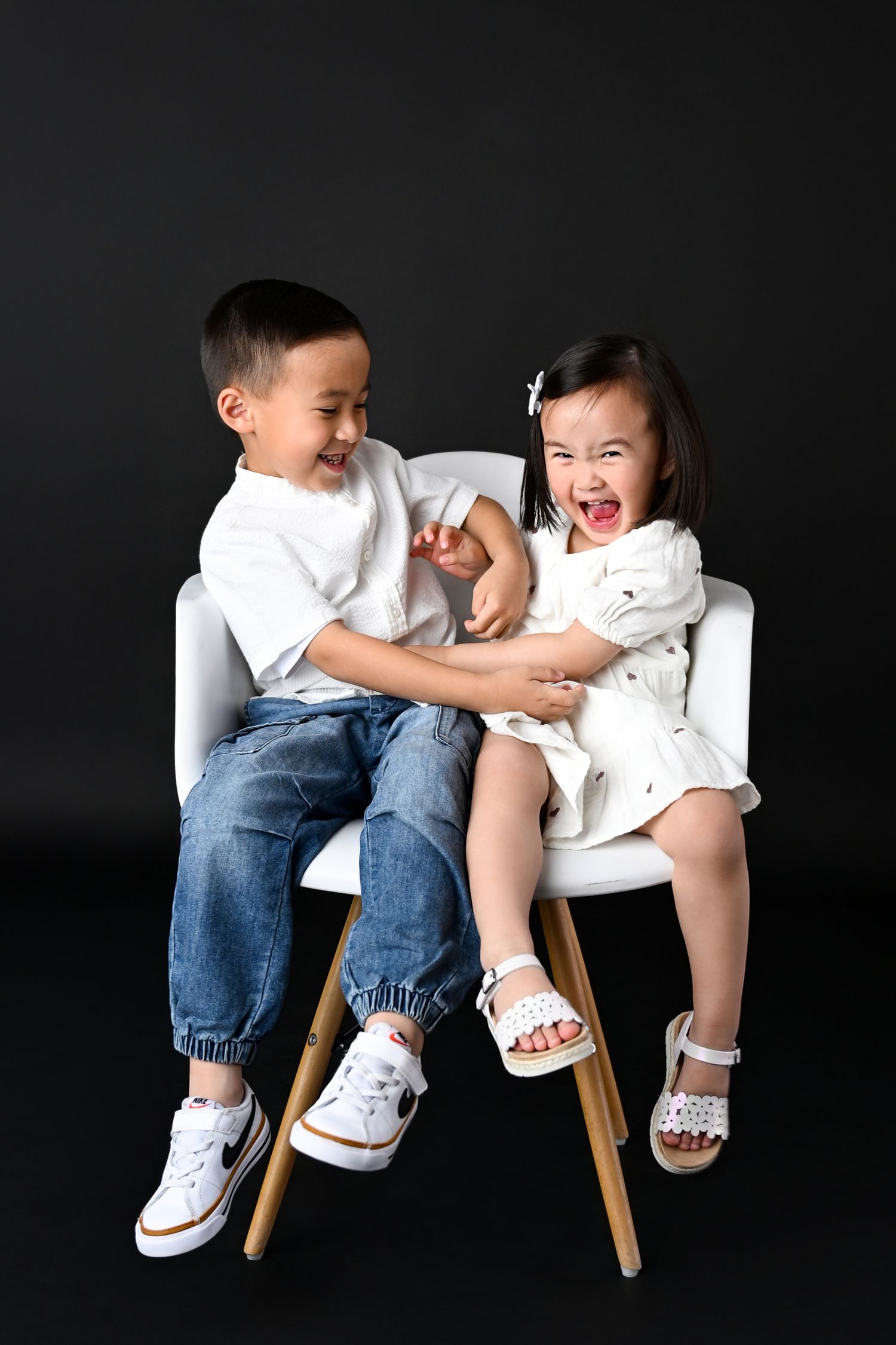 Tickle Fight between toddler siblings on a black studio backdrop